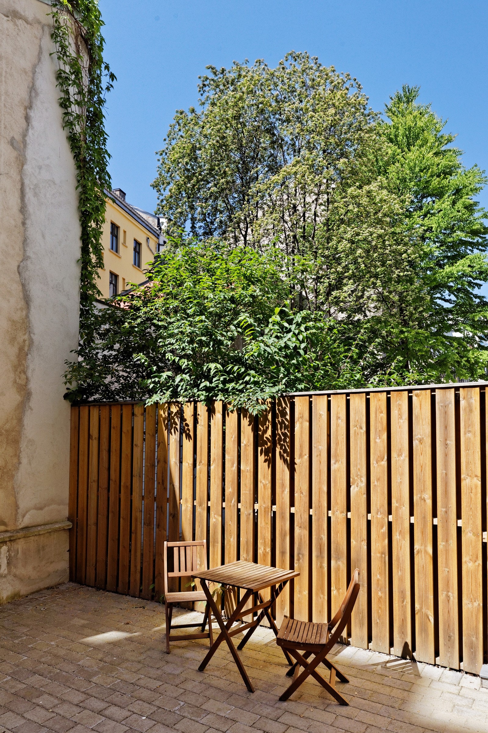 Bakgården er trivelig med steinlagte arealer, sittegruppe og sykkelparkering Galleribilde