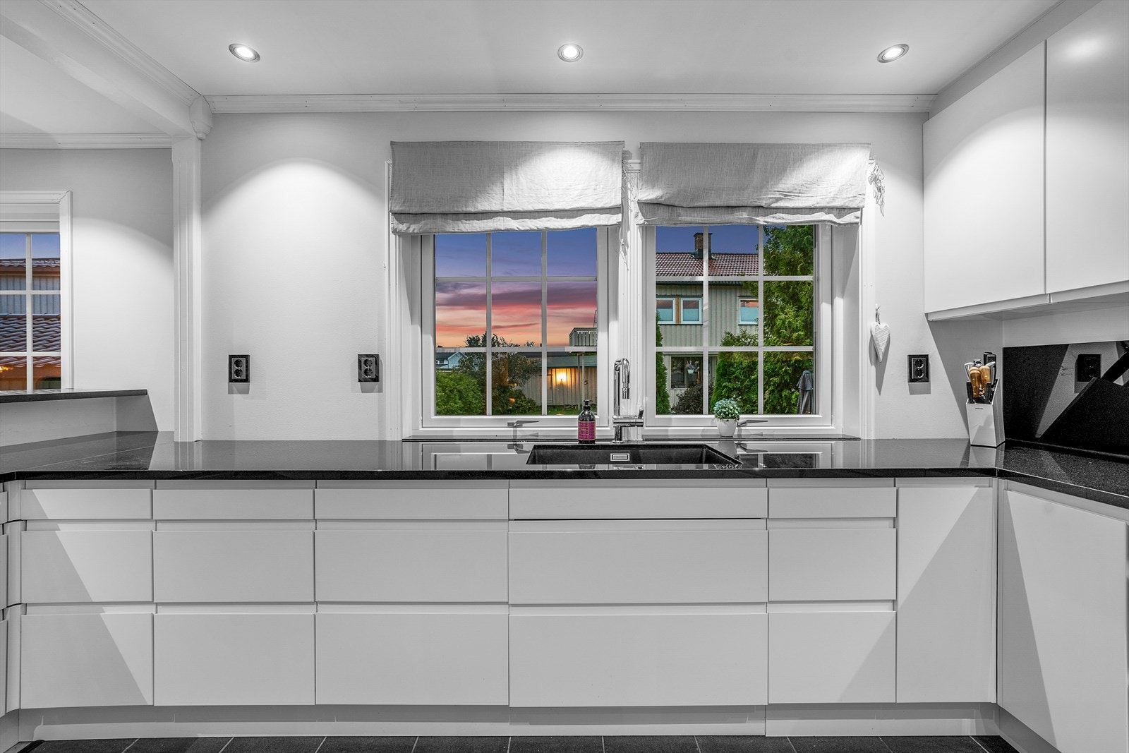 Kjøkkeninnredningen har moderne hvite, slette fronter, er bygget i en smart hesteskoform og godt utstyrt med store kolonialskuffer toppet med benkeplater av granitt. Galleribilde