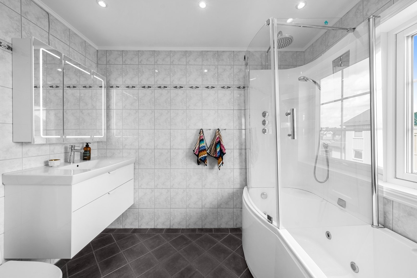 Det andre badet ligger i 2. etasje og er innredet med gulvmontert toalett, et stilrent baderomsmøblement og et badekar. Galleribilde