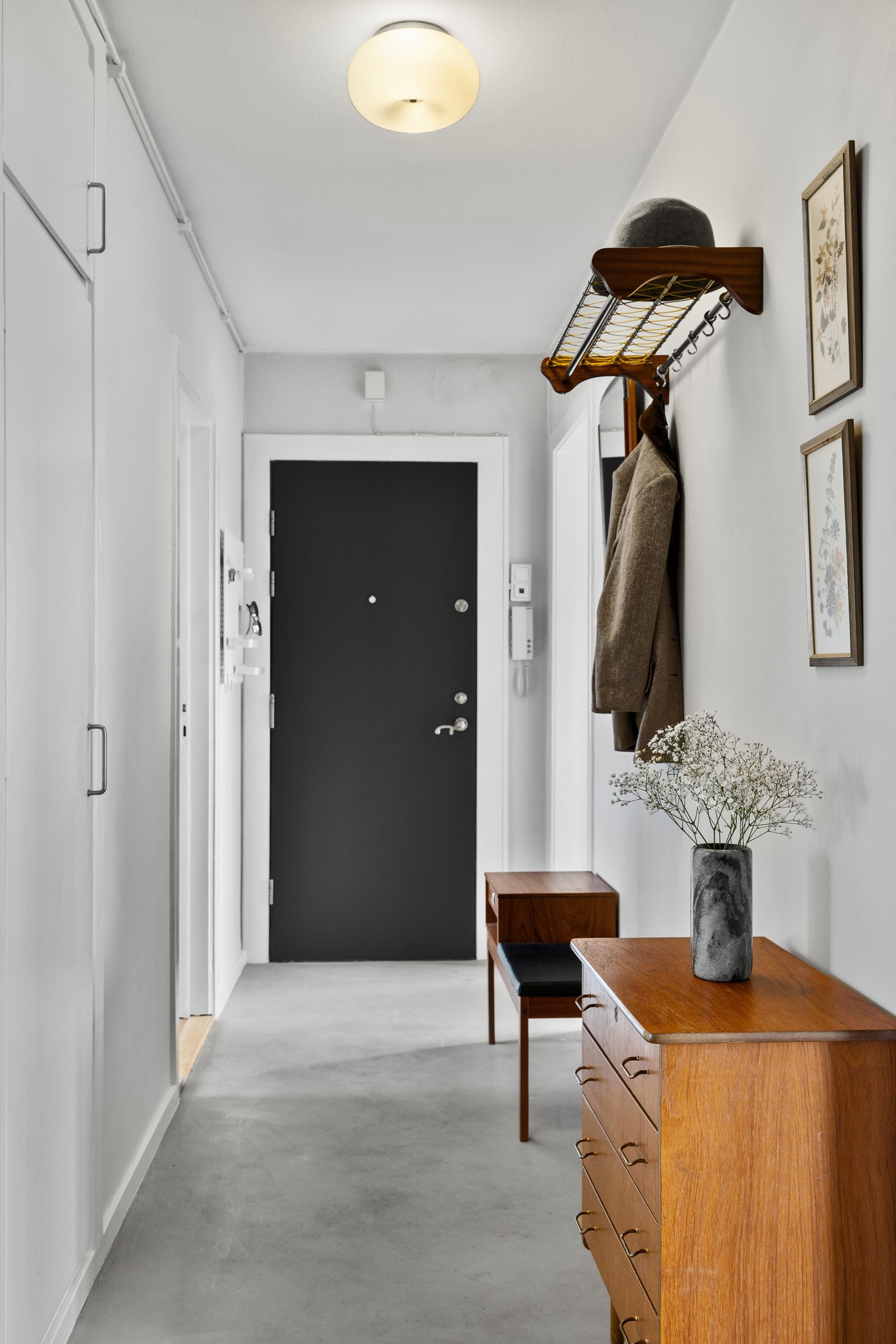 Romslig gang med mikrosement på gulv og slette, lysmalte flater. Det er varmekabler i gulvet. Galleribilde