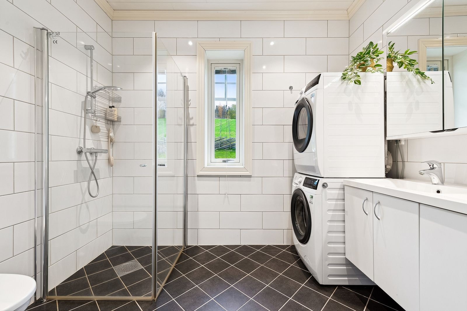 Flislagt baderom med opplegg for vaskemaskin og plass for vaskesøyle. Galleribilde