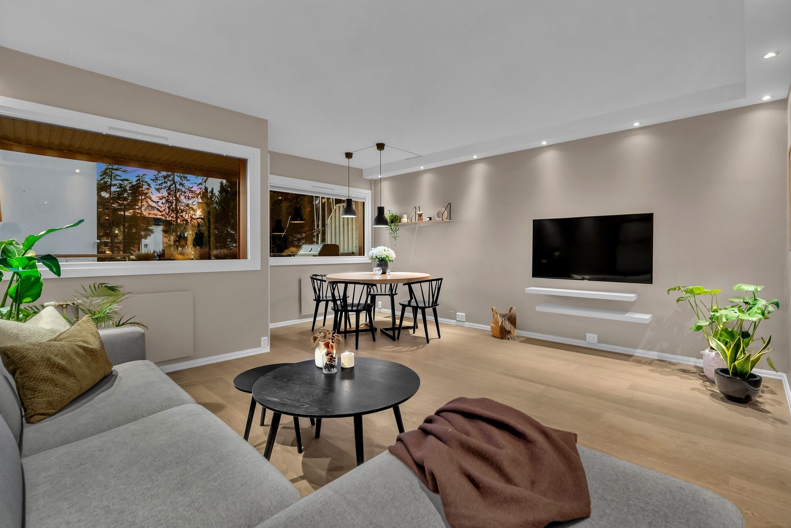 Smakfull innredet stue med pene parkettgulv, slette overflater og delvis nedsenket tak med innfelt downlights. Galleribilde