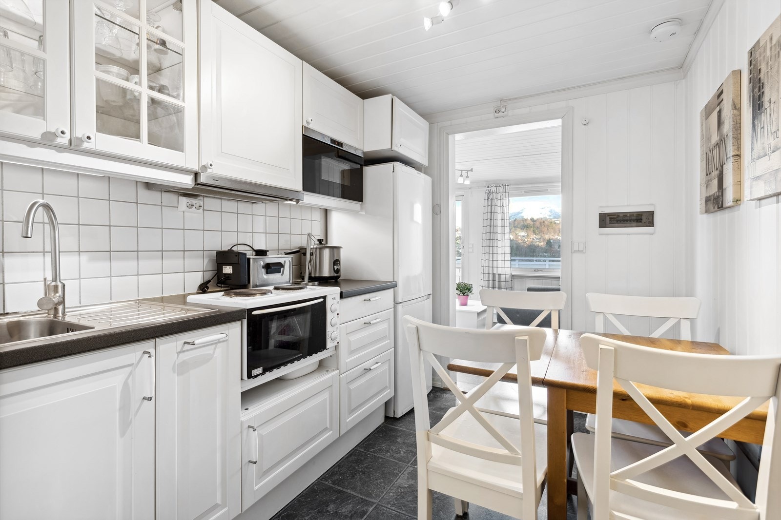 U-etasje, selvstendig boenhet mot vest (ikke godkjent som utleiedel): Hvit kjøkkeninnredning med profilerte fronter, laminat benkeplate og fliser mellom overskap og benkeplate. Her er det også plass til frokostbord. Galleribilde