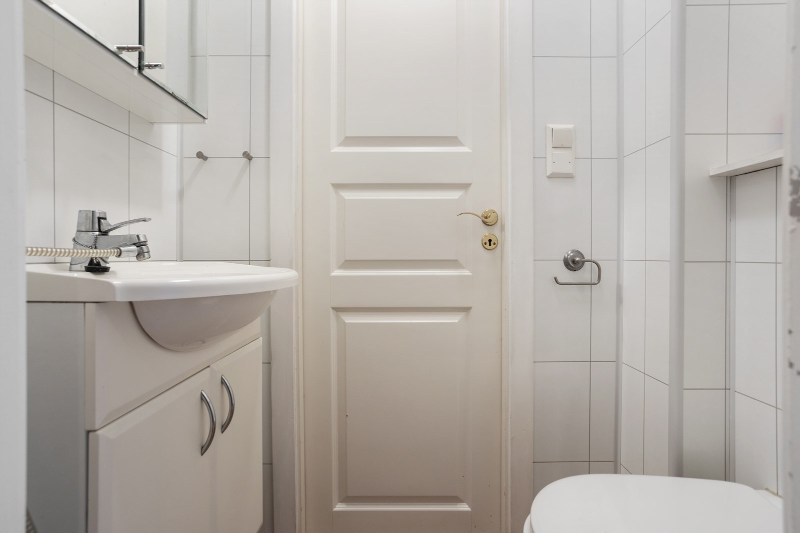 1.etasje, hoveddel: Toalettrom med fliser på gulv og baderomsplater på vegger. Det inneholder vegghengt toalett og baderomsinnredning med servant og overhengende speilskap. Galleribilde