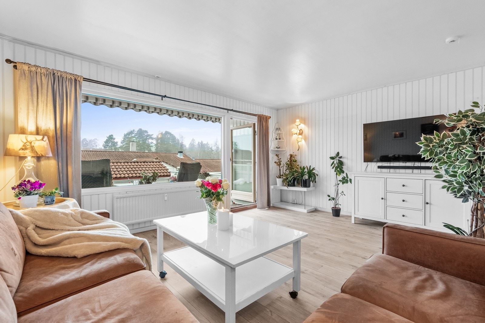 Stuen er et lyst og trivelig rom med hvitmalte panelplater på veggene og med et pent laminatgulv. Galleribilde