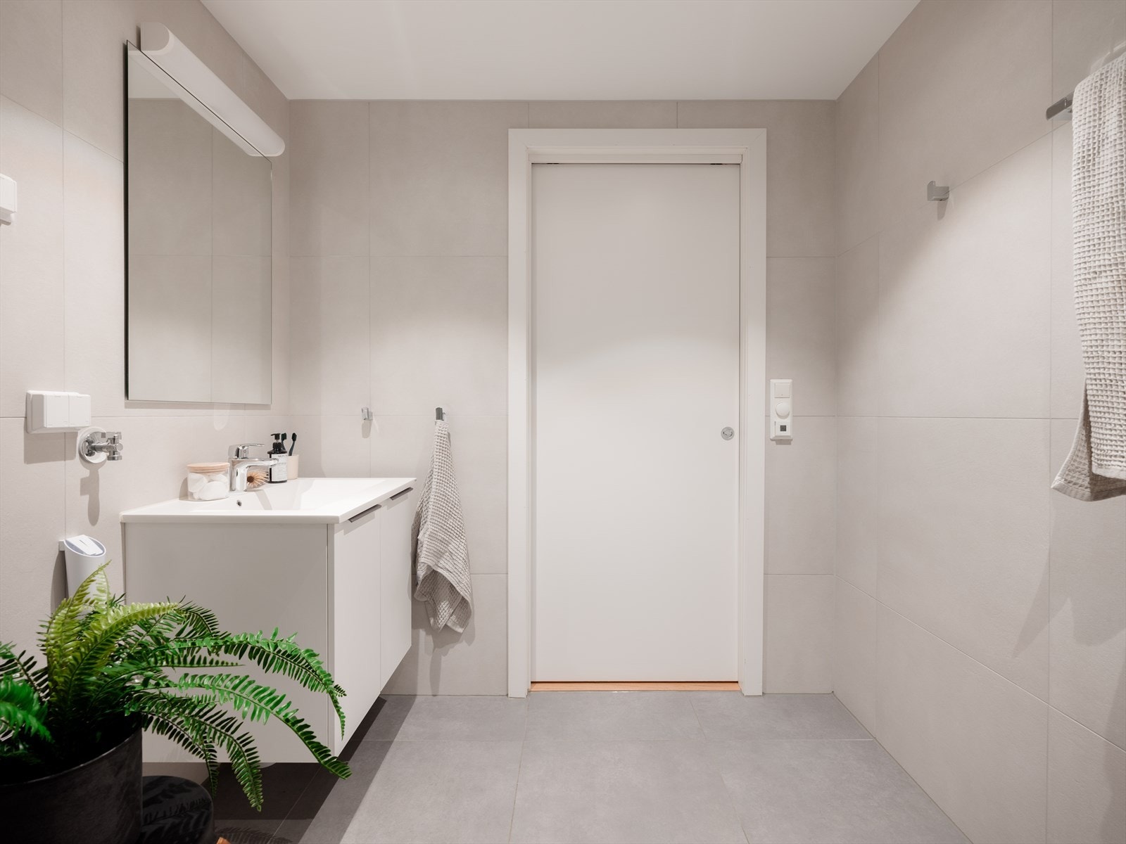Badet er innredet med vegghengt toalett, dusjhjørne og servant på underliggende servantskap. Galleribilde