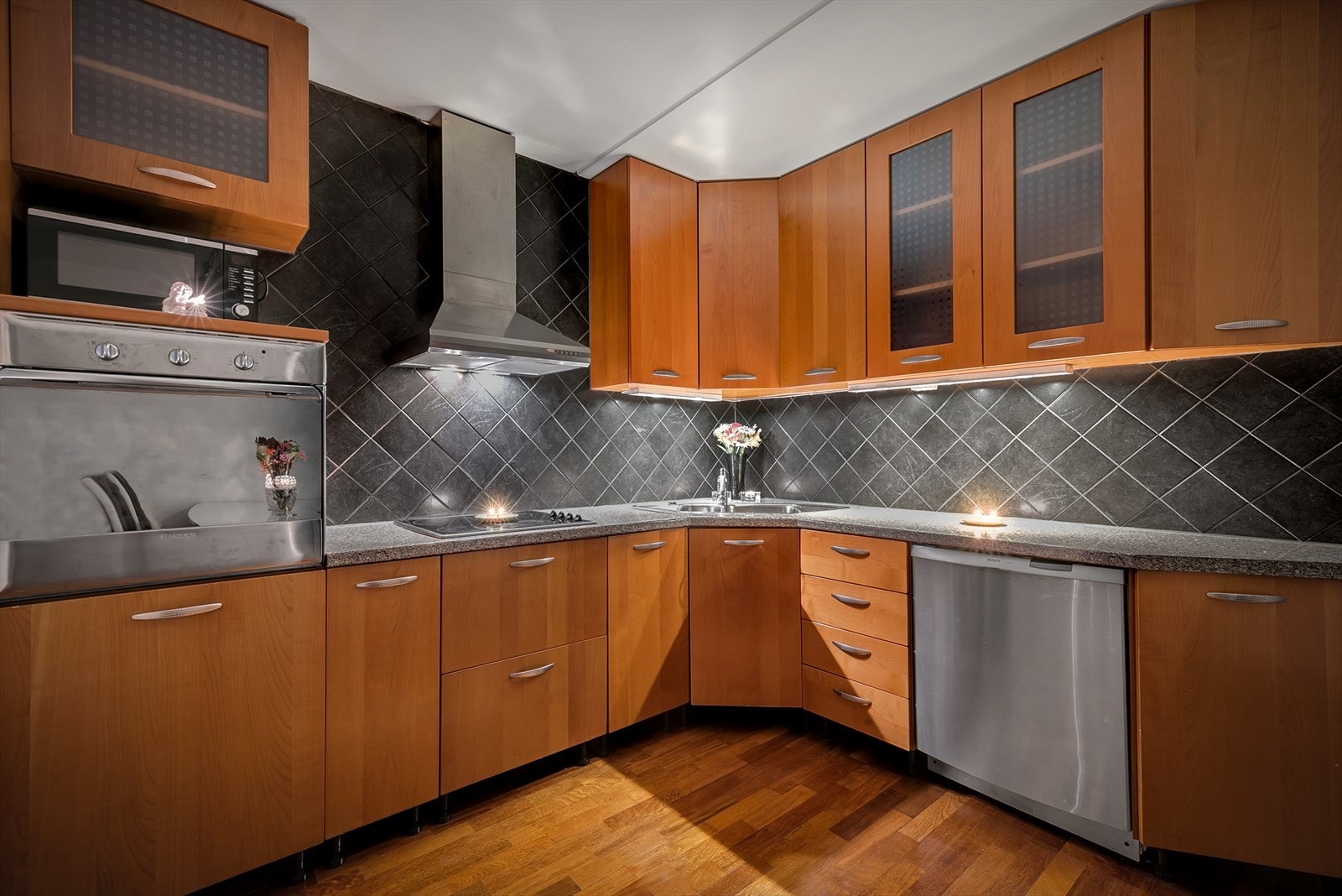 Kjøkkeninnredning med slette kirsebærfronter, fliser mellom over- og underskap og integrert stekeovn og koketopp. Galleribilde