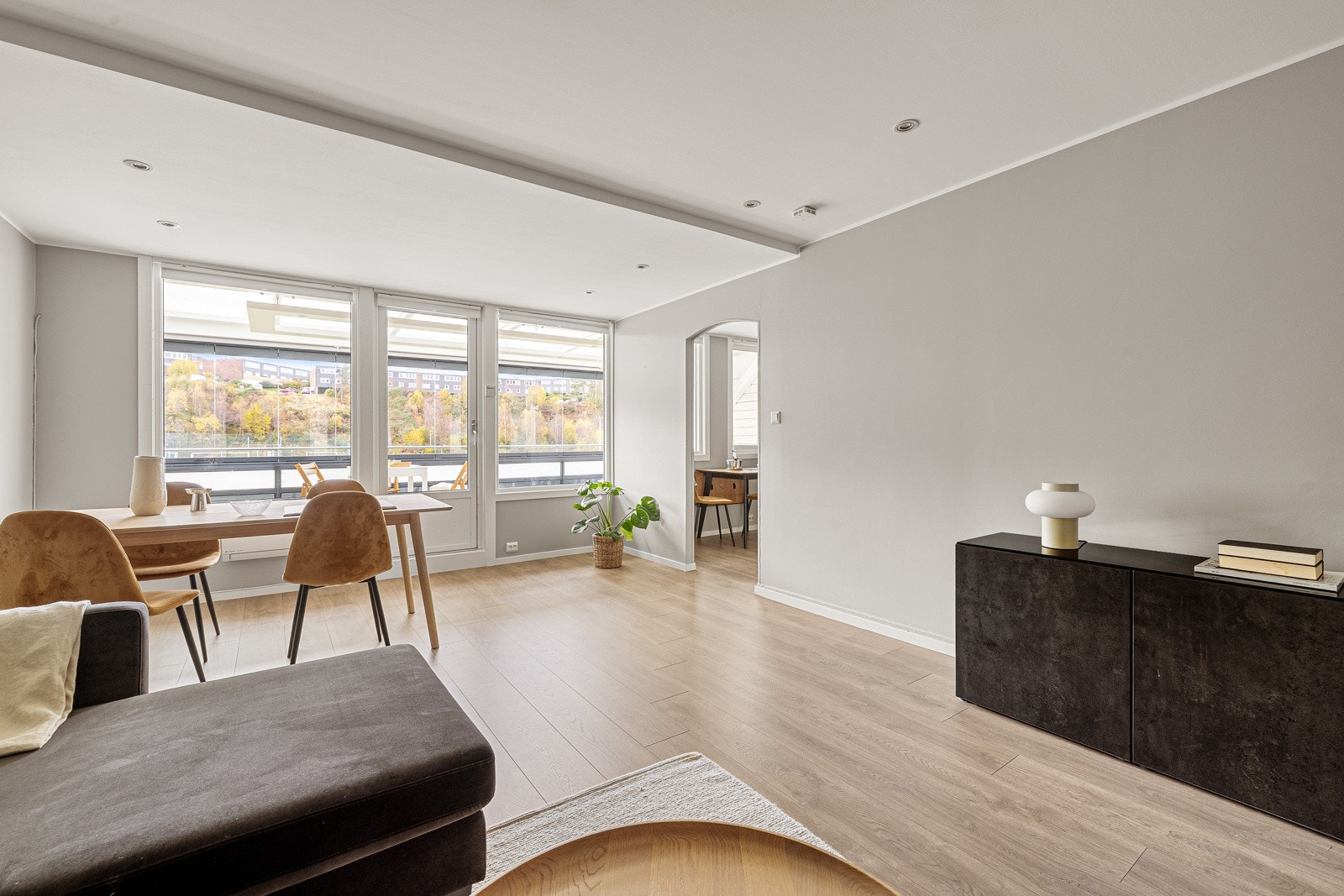 Som i store deler av leiligheten er det på stuen også 1-stavs laminat i gulv og vegger og himling malt i en lys fargetone. Galleribilde