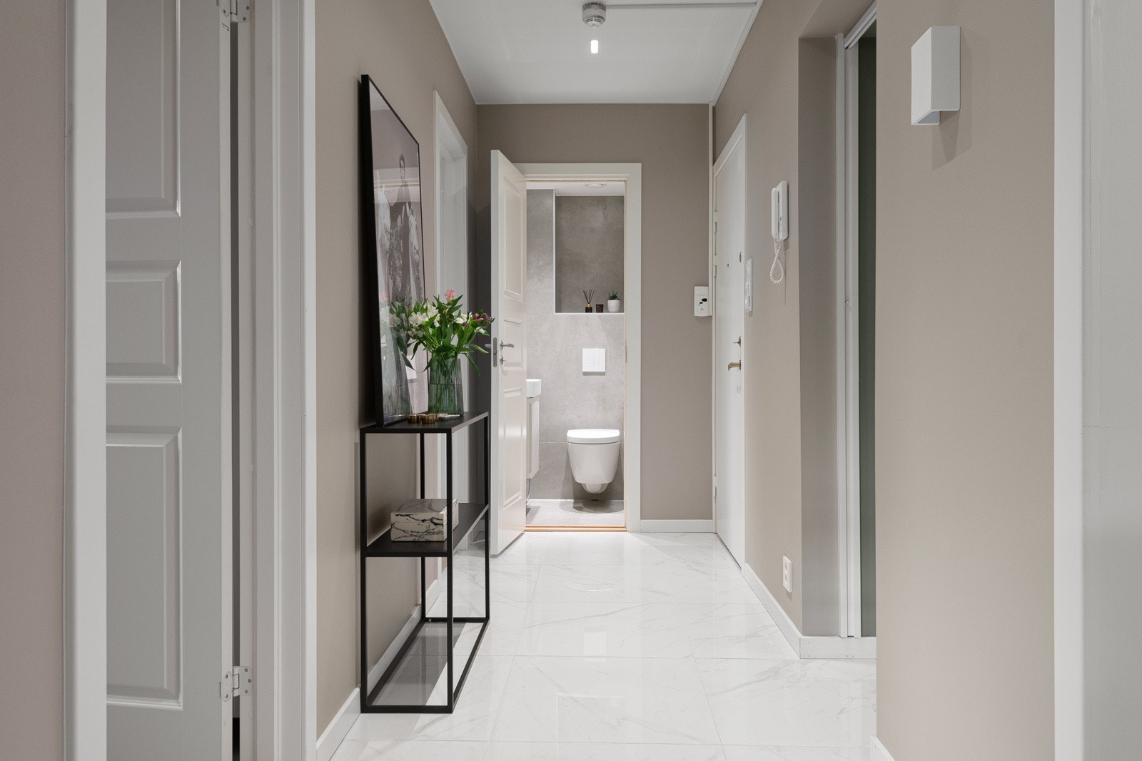 Entréen har åpninger mot flere av leilighetens øvrige rom, slik at dagslyset fritt kan strømme gjennom og bidra til en lysere atmosfære i disse rommene. Det er plass til oppbevaring av sko og yttertøy i kottet. Galleribilde