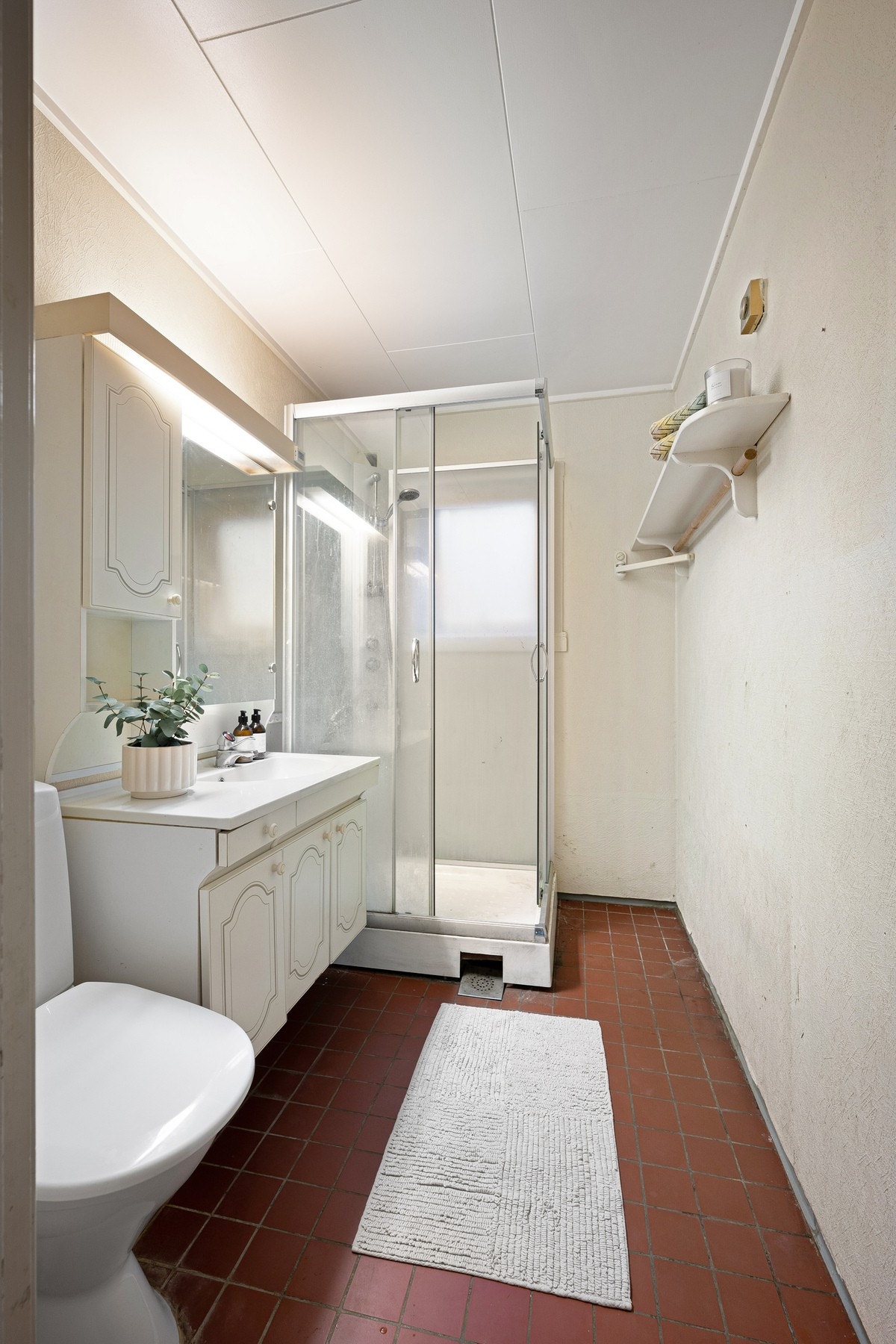 Badet har flislagt gulv og inneholder servantinnredning, wc og dusjkabinett Galleribilde