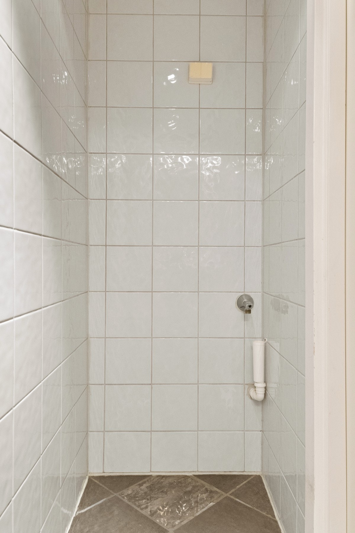 Badet er utstyrt med en dusjsone, gulvstående toalett og opplegg for vaskemaskin. Galleribilde