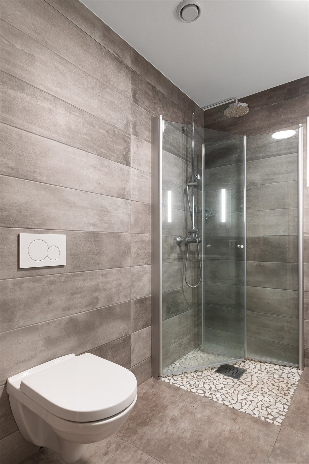 Badet er utstyrt med servant med underskap, dusjnisje med innfellbare glassdører og regndusj, opplegg for vaskemaskin, samt veggmontert toalett Galleribilde