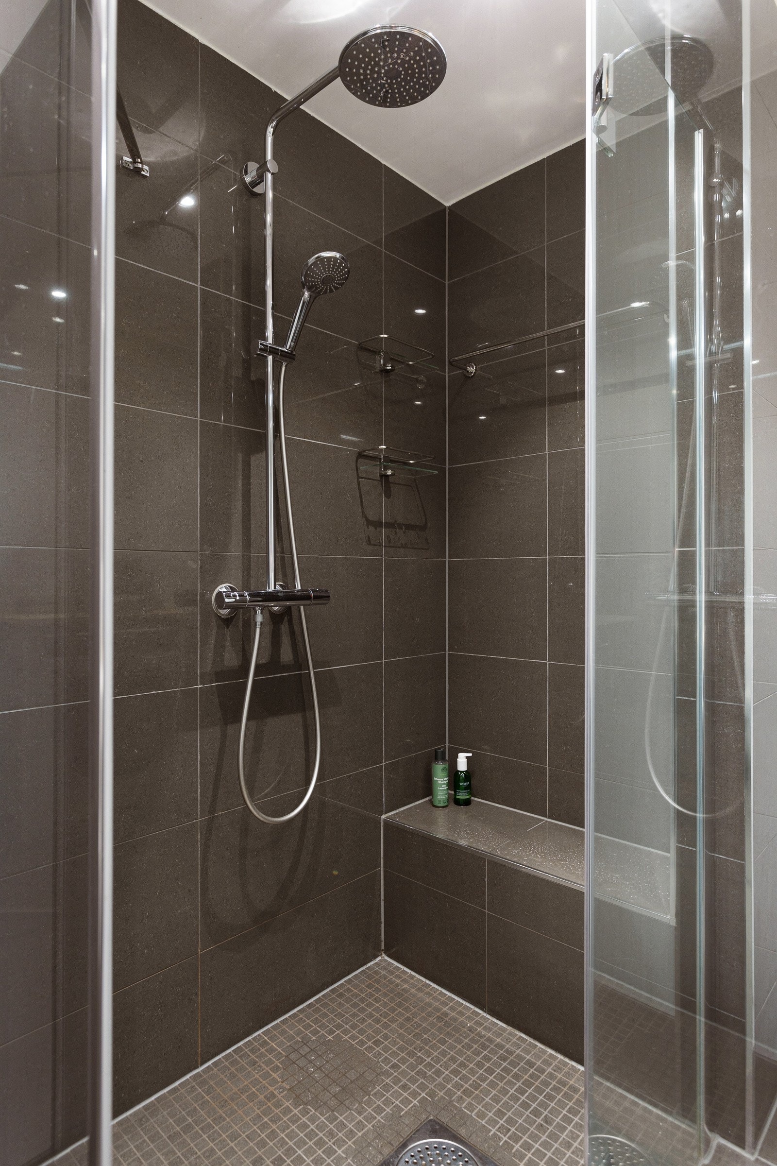 Dusjhjørne med praktisk benk og glassdører Galleribilde