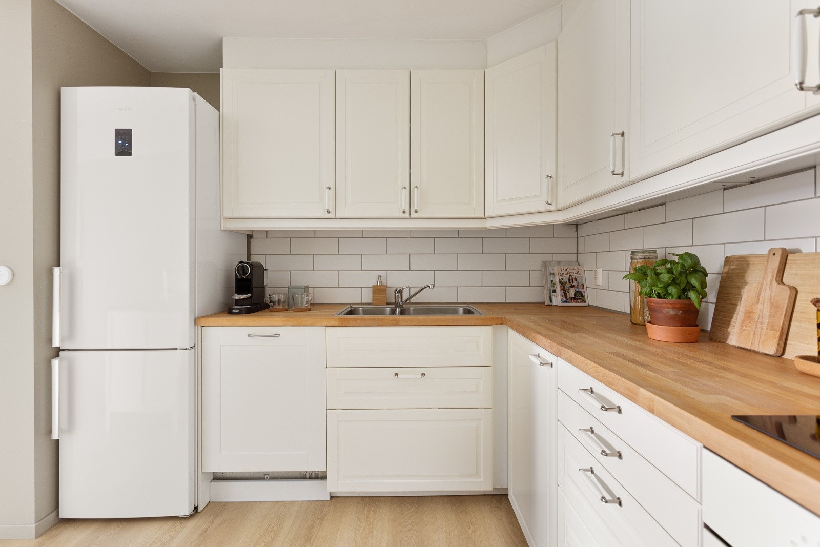 Kjøkkenet er utstyrt med Integrert oppvaskmaskin, frittstående kjøleskap med frysedel, benkeplate av heltre. Det er flislagt mellom overskap og underskap. Galleribilde