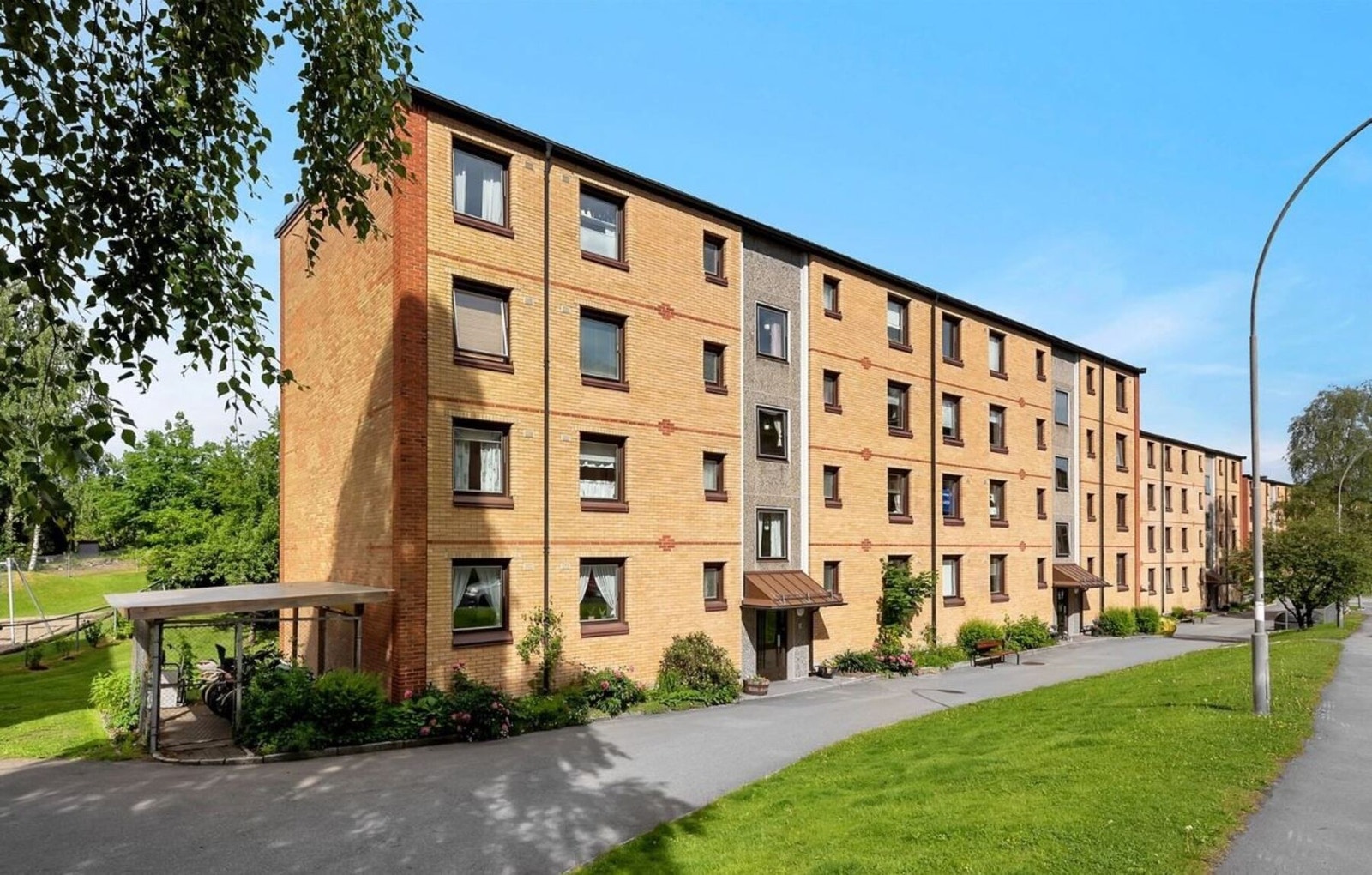 Borettslaget har en etterspurt beliggenhet i fredelig blindvei. Her vises fasade fra inngangspartiet hvor boligen ligger i meget høy 1. etasje, en trapp opp. Galleribilde