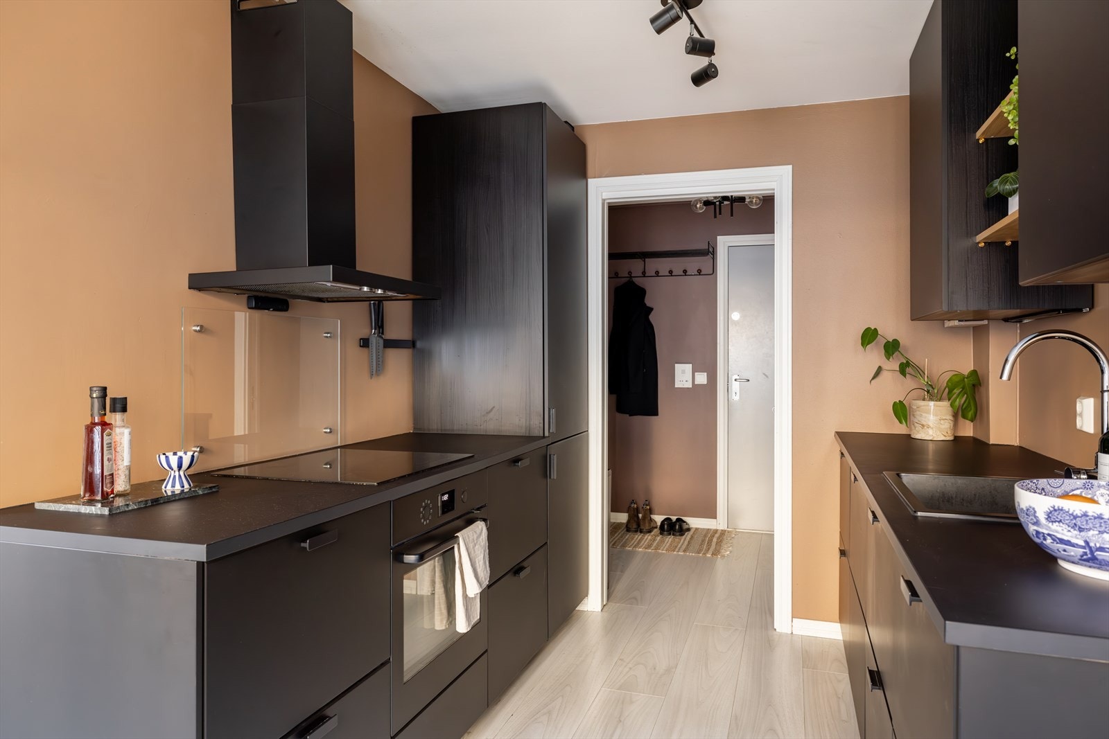 Moderne Ikea-kjøkken fra 2020 med stilrene, sorte fronter og slitesterk laminatbenkeplate. Praktiske løsninger inkluderer integrerte hvitevarer som kjøle-/fryseskap, oppvaskmaskin, stekeovn og induksjonstopp. Galleribilde