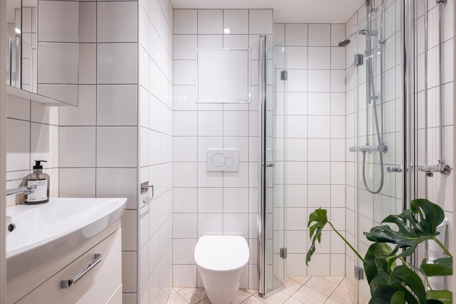 Badet er innredet med heldekkende servant på underskap, speil med belysning, vegghengt toalett og en dusjløsning med herdet glassvegger. Galleribilde