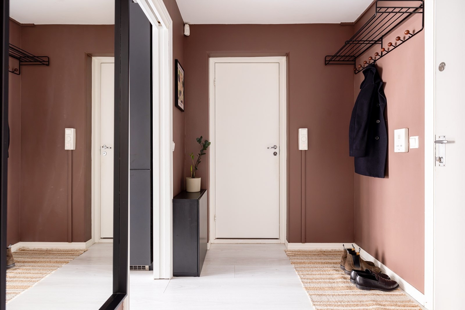 En innbydende entré som gir et godt førsteinntrykk av leiligheten. Her er det god plass til oppbevaring av yttertøy og sko, samtidig som gangen fremstår som praktisk og ryddig. Galleribilde