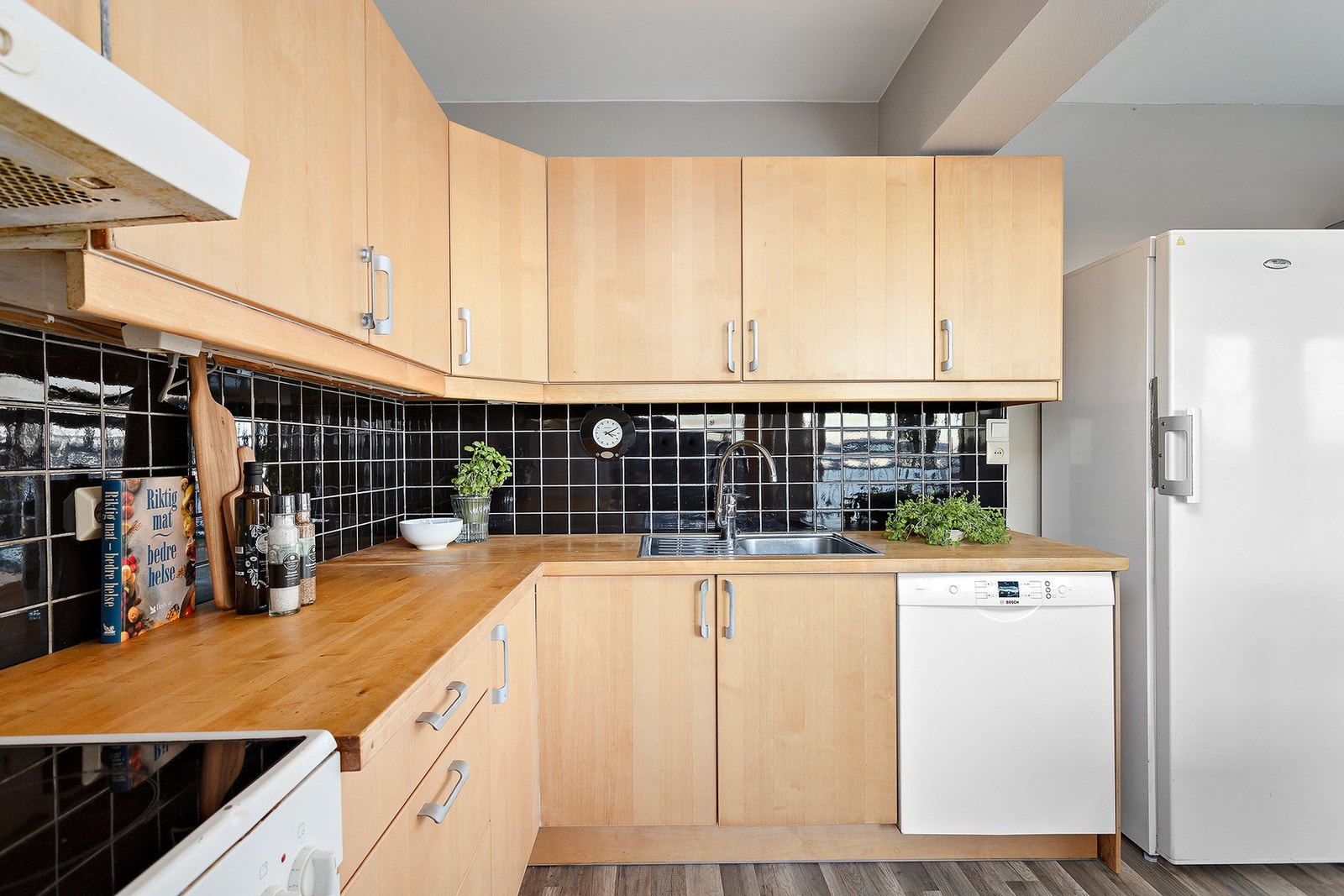 Pen IKEA kjøkkeninnredning fra ca. 2010. Kjøkkenet er utført med glatte fronter og laminat benkeplate. Her er det rikelig med benkeplass samt oppbevaring av kjøkkenredskaper. Galleribilde