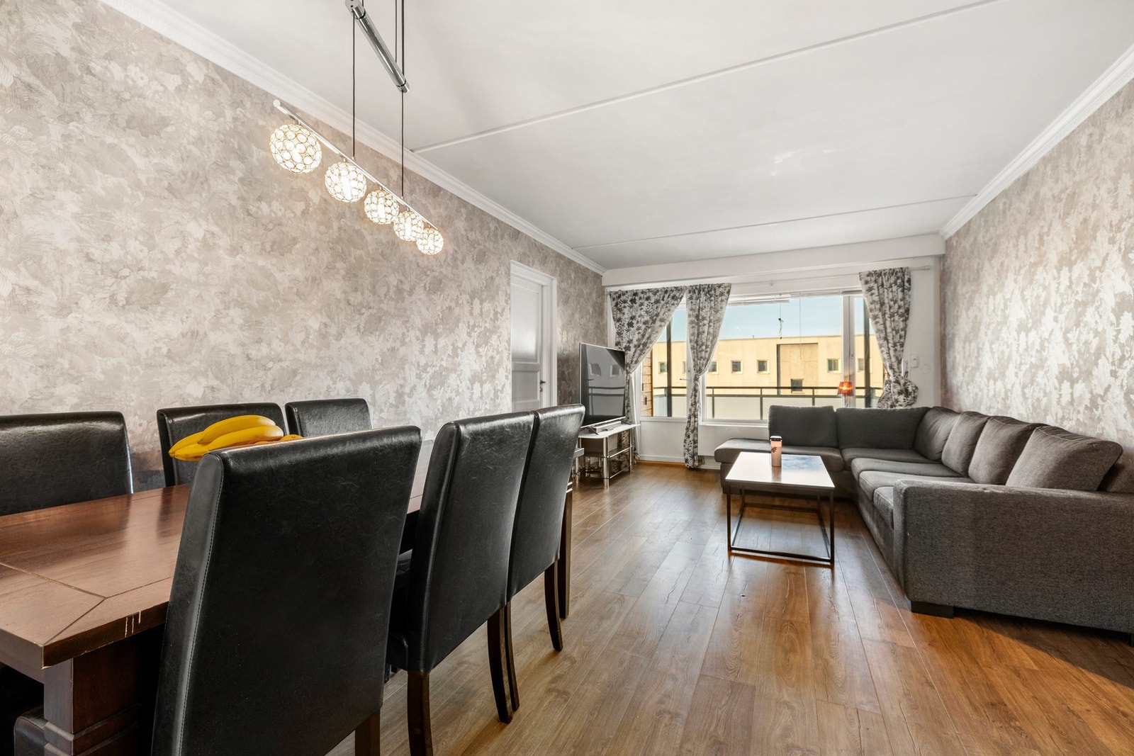 Leiligheten har en romslig stue med plass til både stor sofa, mediemøblement og spisestue Galleribilde