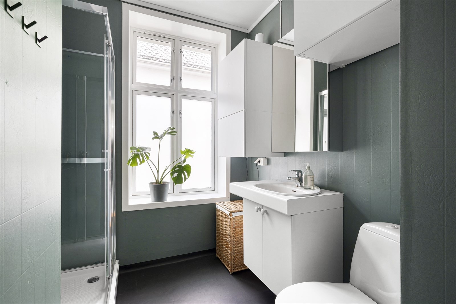 Baderommet er innredet med dusjkabinett, toalett, vask i seksjon og vegghengte skap. Det er klart opplegg for vaskemaskin men da må en enten ha en liten vaskemaskin eller bytte til en mindre benkeplate på servant Galleribilde