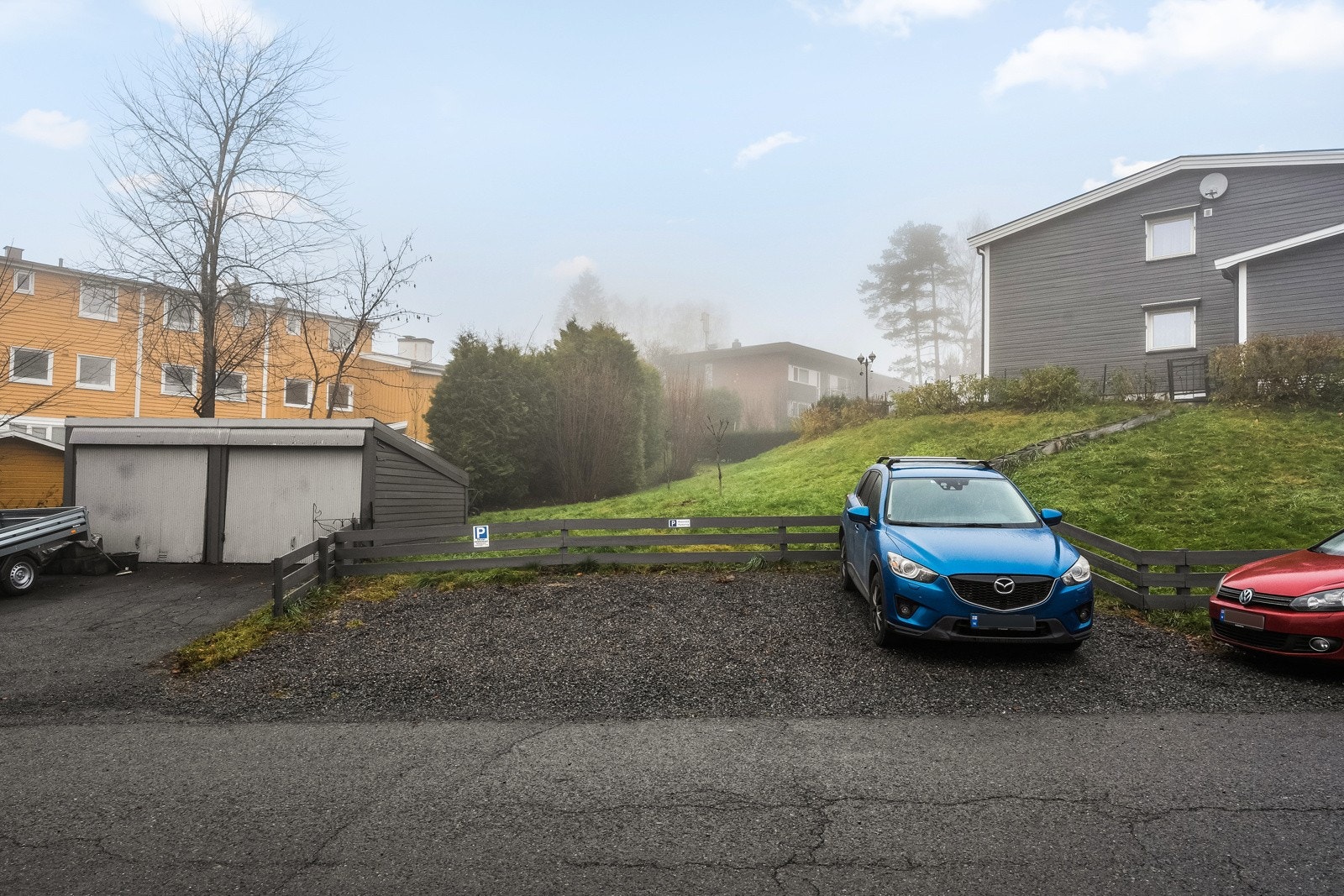 Med boligen følger en dedikert parkeringsplass på sameiets tomt. Den midterste av parkeringsplassene i bildet tilhører enheten Galleribilde