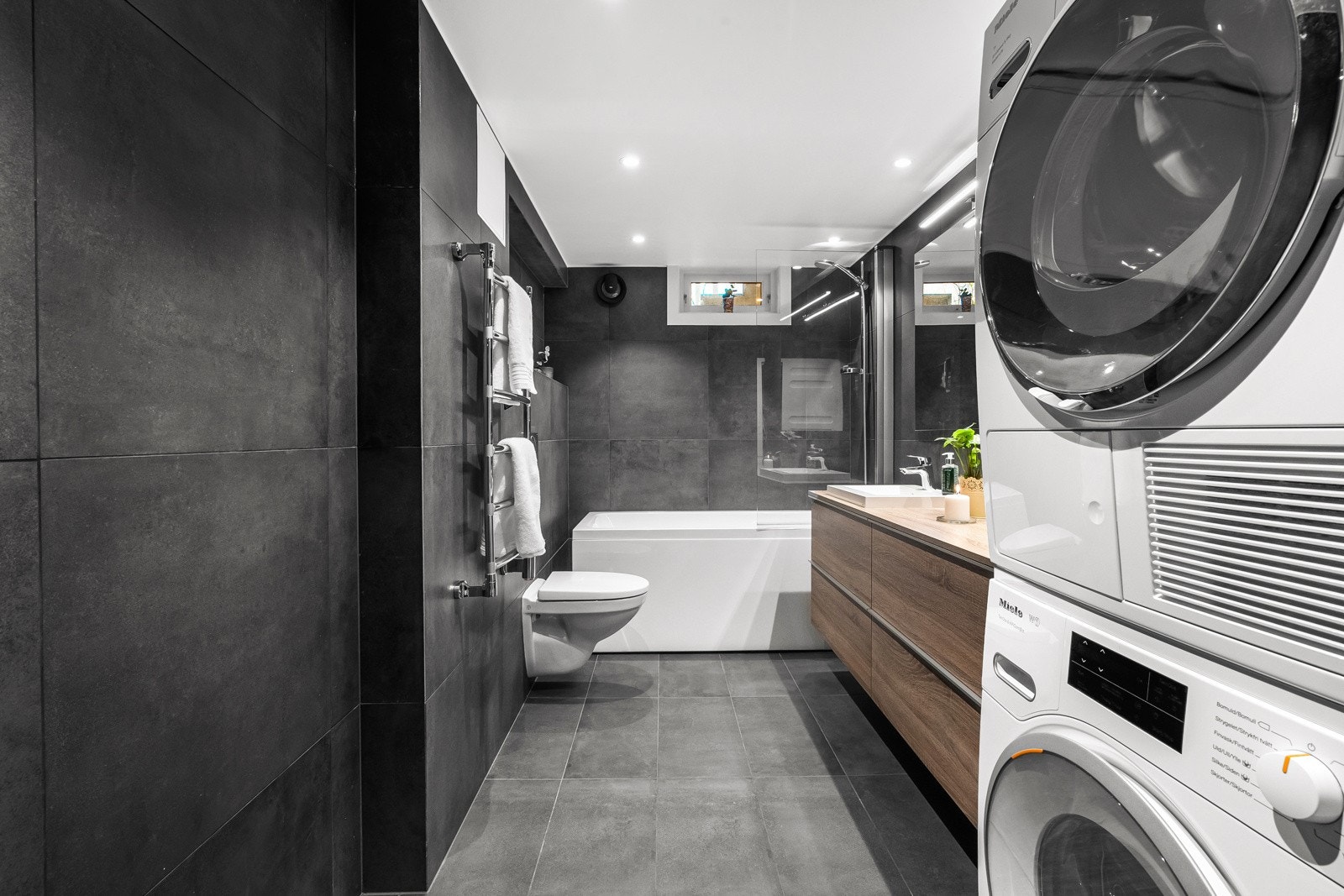 Flislagt bad fra 2021 med frittstående badekar og termostatstyrt dusjbatteri i krom med både kran og hånddusj Galleribilde