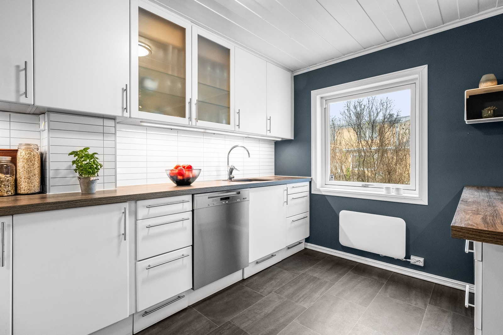 Kjøkkenet har mørk laminat benkeplate med elegant, planlimt sort komposittvask og ett-greps armatur i krom Galleribilde