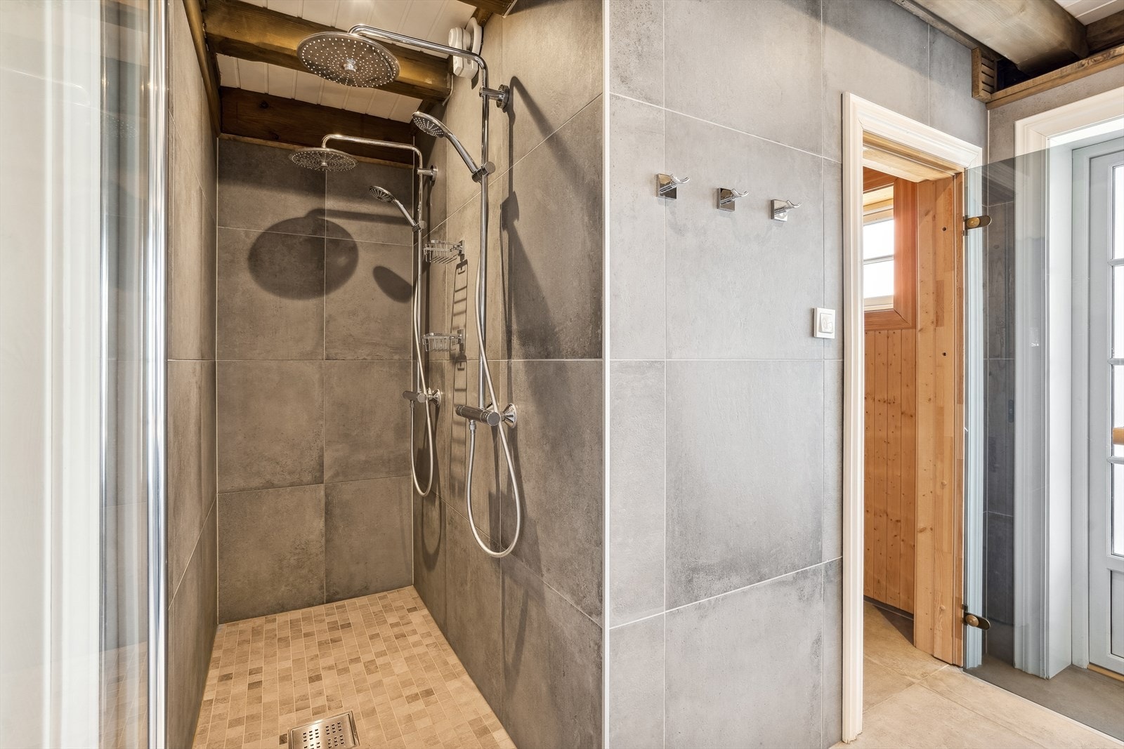 Videre har badet en dusjnisje med glassdør og dobbel dusjarmatur med regndusj. Galleribilde