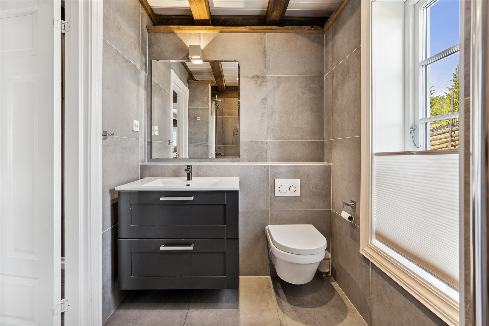 Badet er innredet med vegghengt servantinnredning med skuffer og vegghengt toalett. Galleribilde