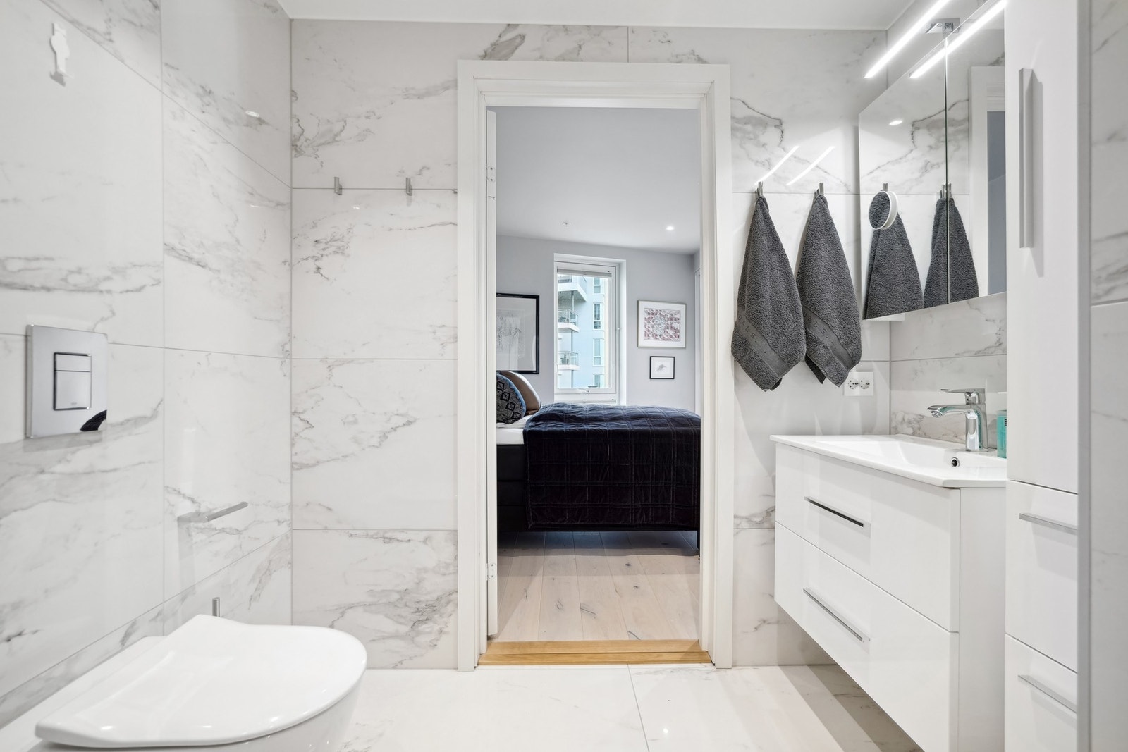 Bad 1: Baderomsinnredningen inkluderer veggmonterte toalett med softclose fra Villeroy Boch, samt høyglans høyskap, speilskap og underskap. Galleribilde