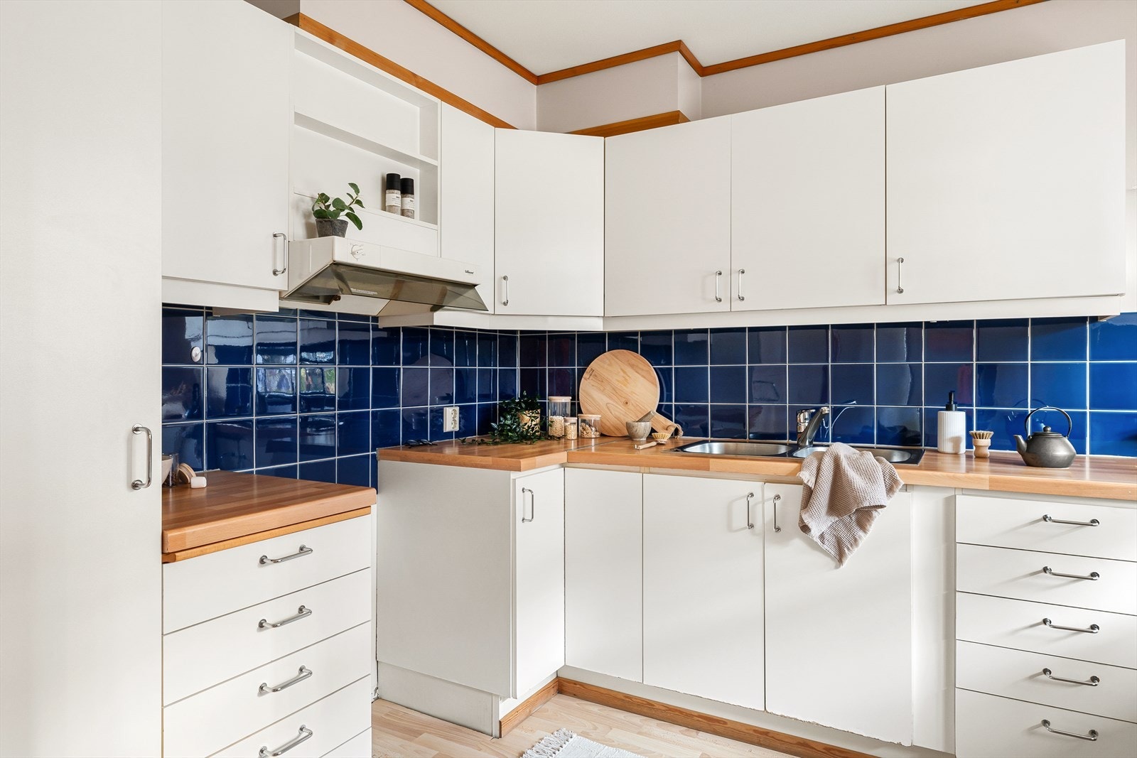 Kjøkken i hvit slett utførelse med laminat benkeplate med fliser over. Galleribilde