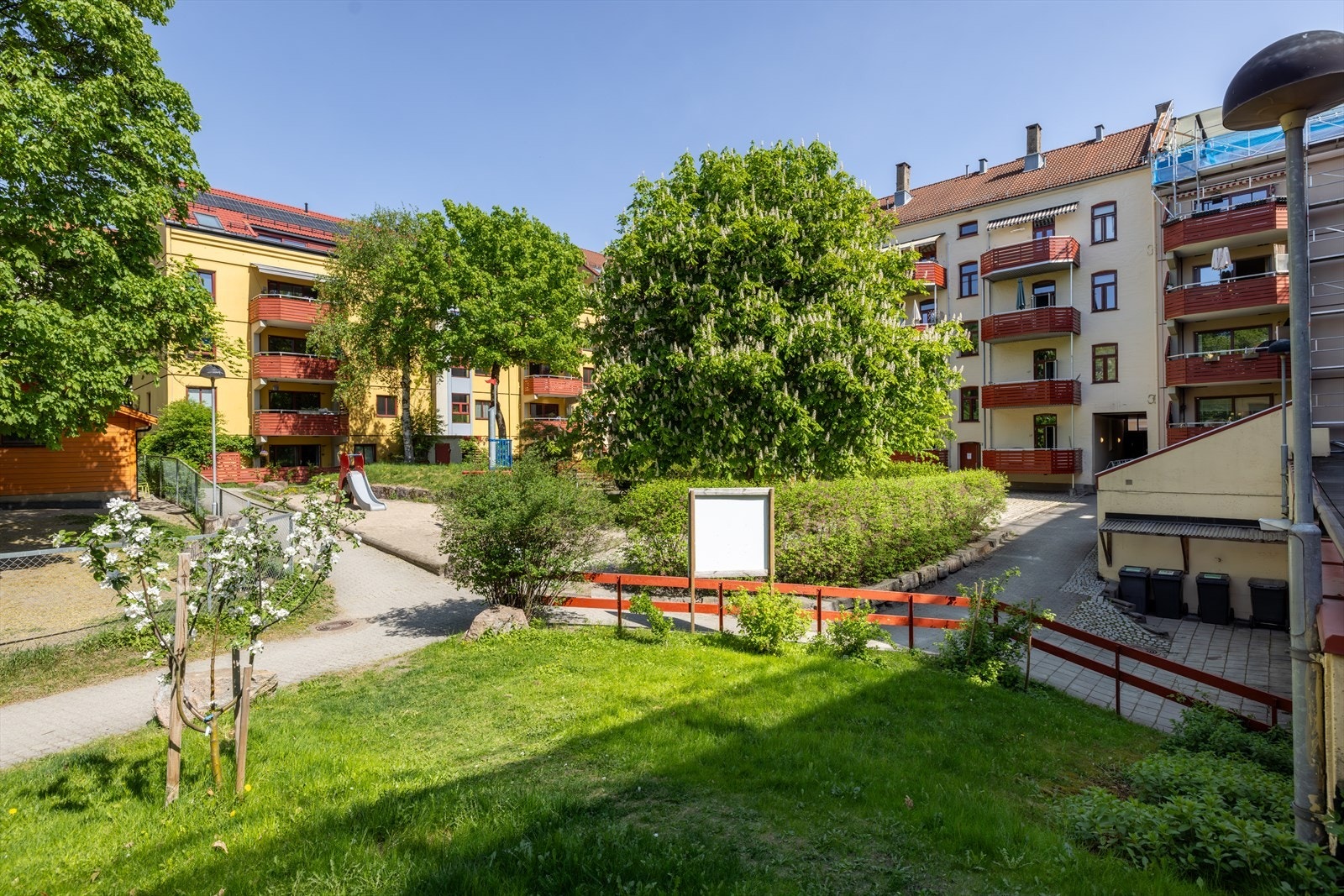 Skjermet bakgård med store grøntarealer, sittegrupper og lekeapparater. Galleribilde