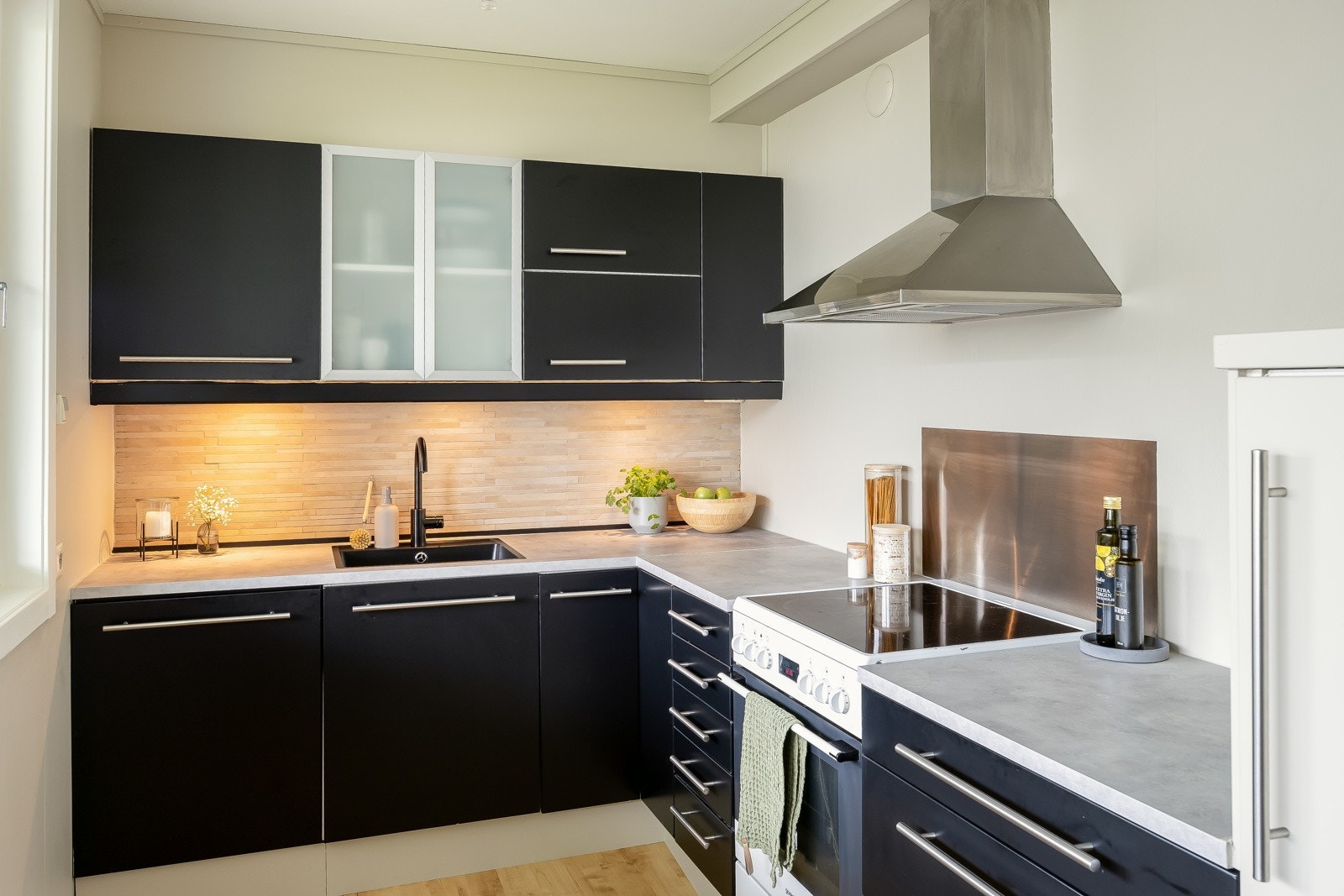 Stilren innredning fra Ikea med integrerte oppvaskmasin og kjøleskap. Mekanisk avtrekk over komfyr. Galleribilde