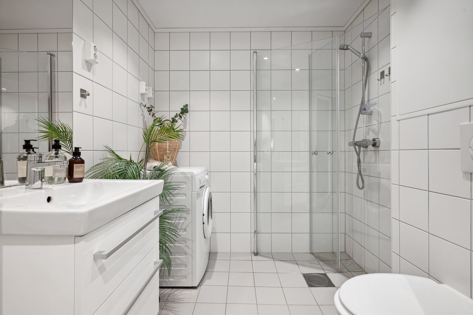 Pent flislagt bad med dusjhjørne, vegghengt wc og opplegg for vaskemaskin. Galleribilde