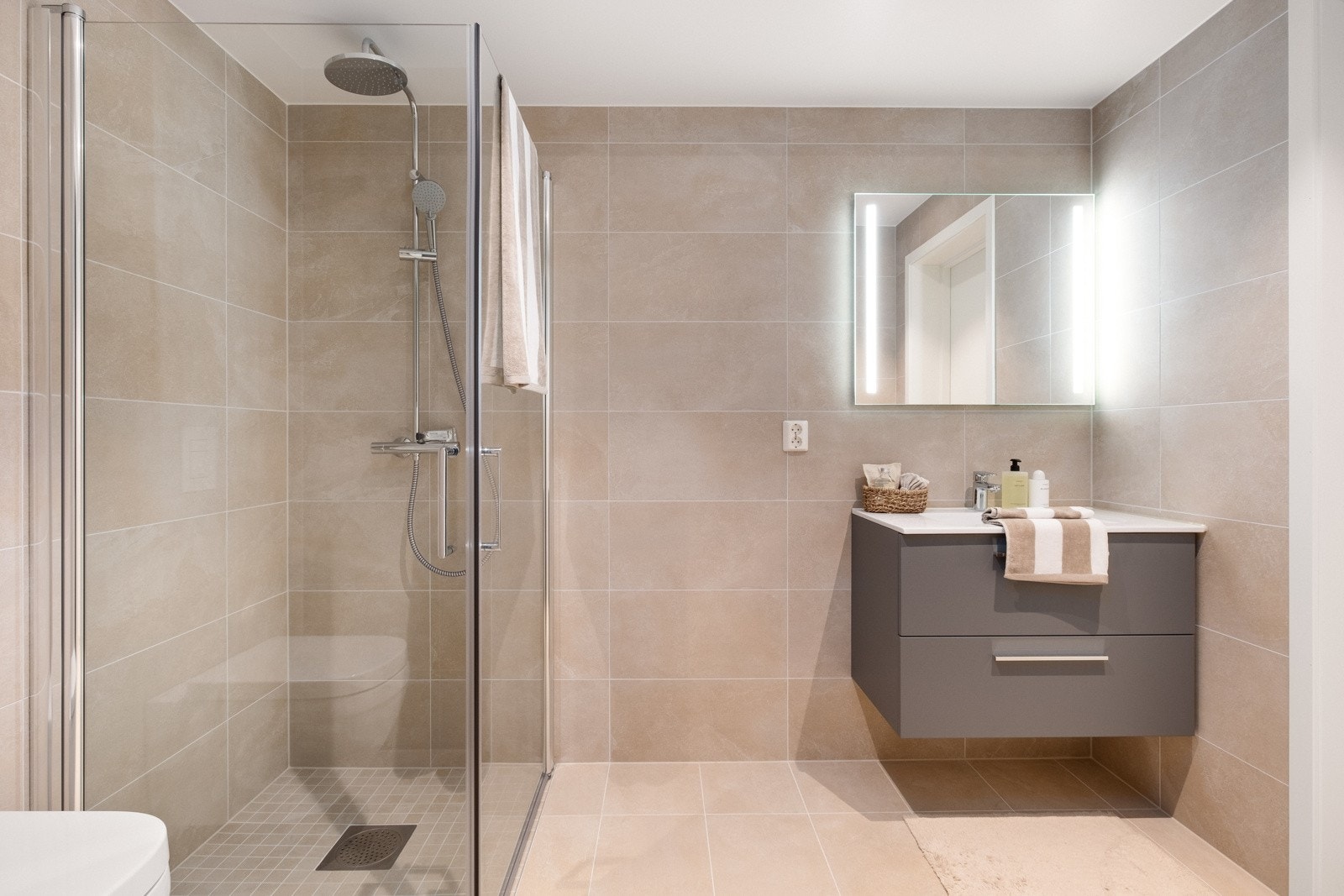 Baderommet måler 5 kvm og har i likhet med boligens andre bad lyse pene fliser i fargen Kintetic Antracite Galleribilde