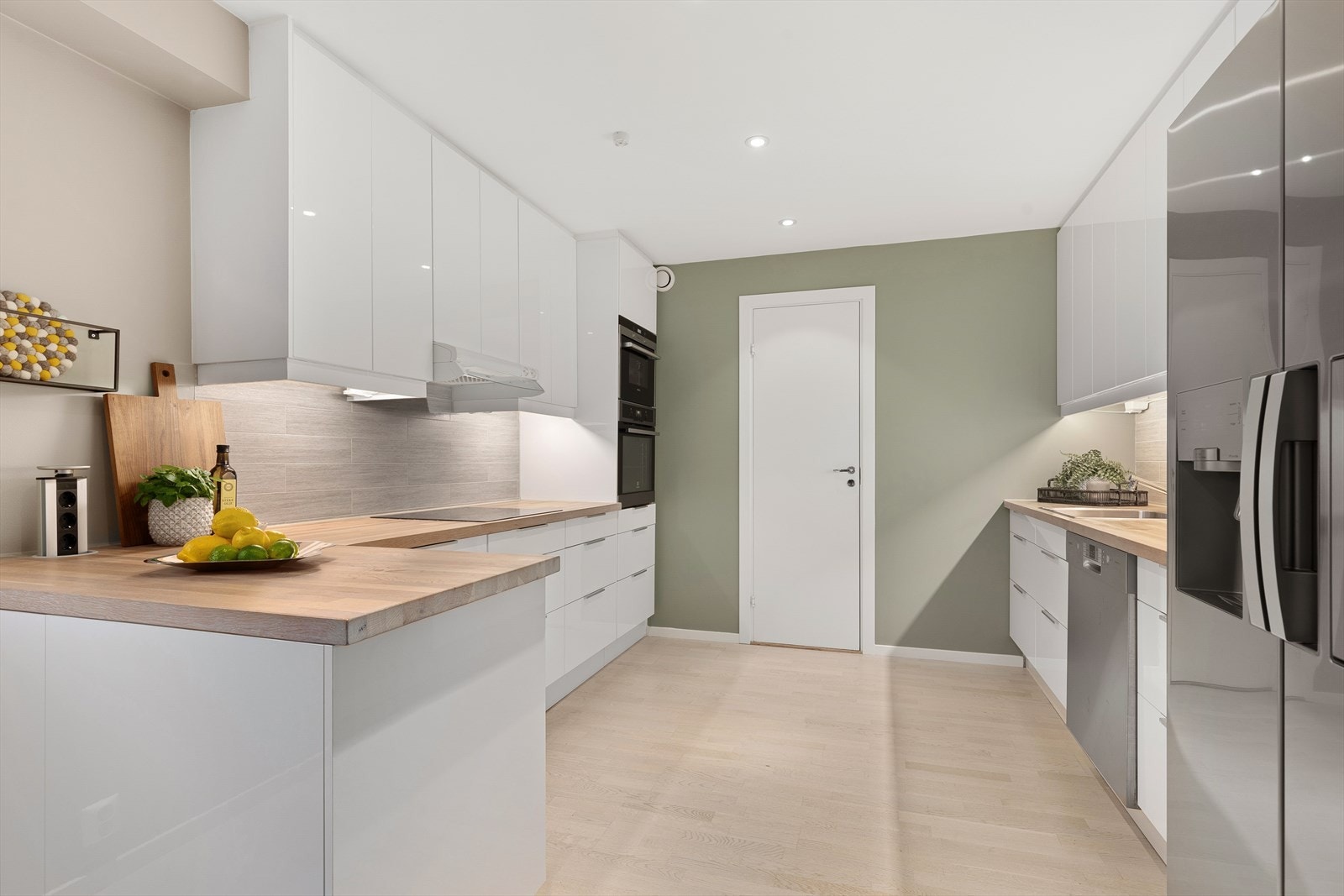 Innredningen har hvite slette fronter og benkeplate i tre med nedfelt oppvaskkum Galleribilde