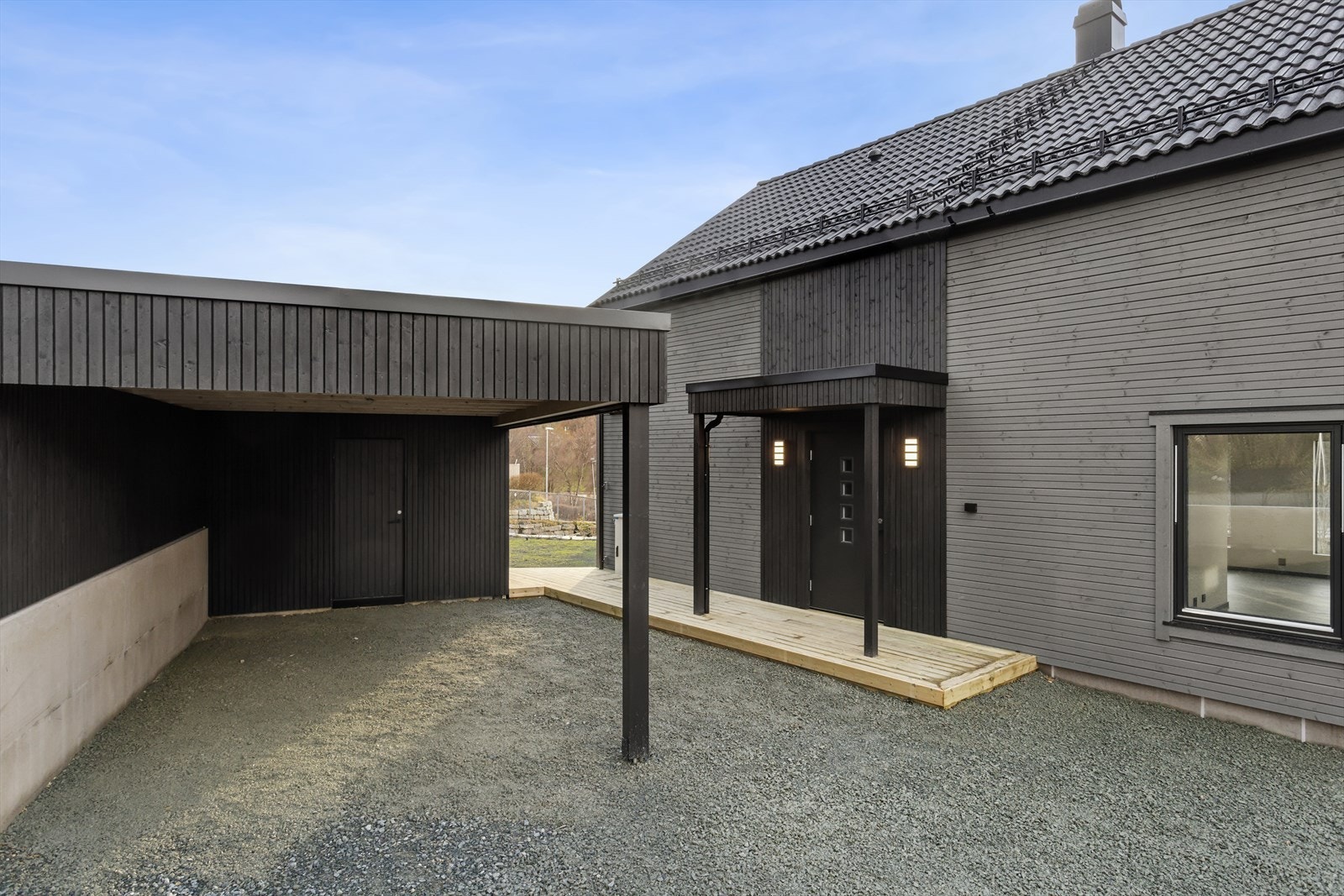 Innkjørsel og carport med bod i bakkant. Hyggelig inngangsparti med terrasse. Galleribilde