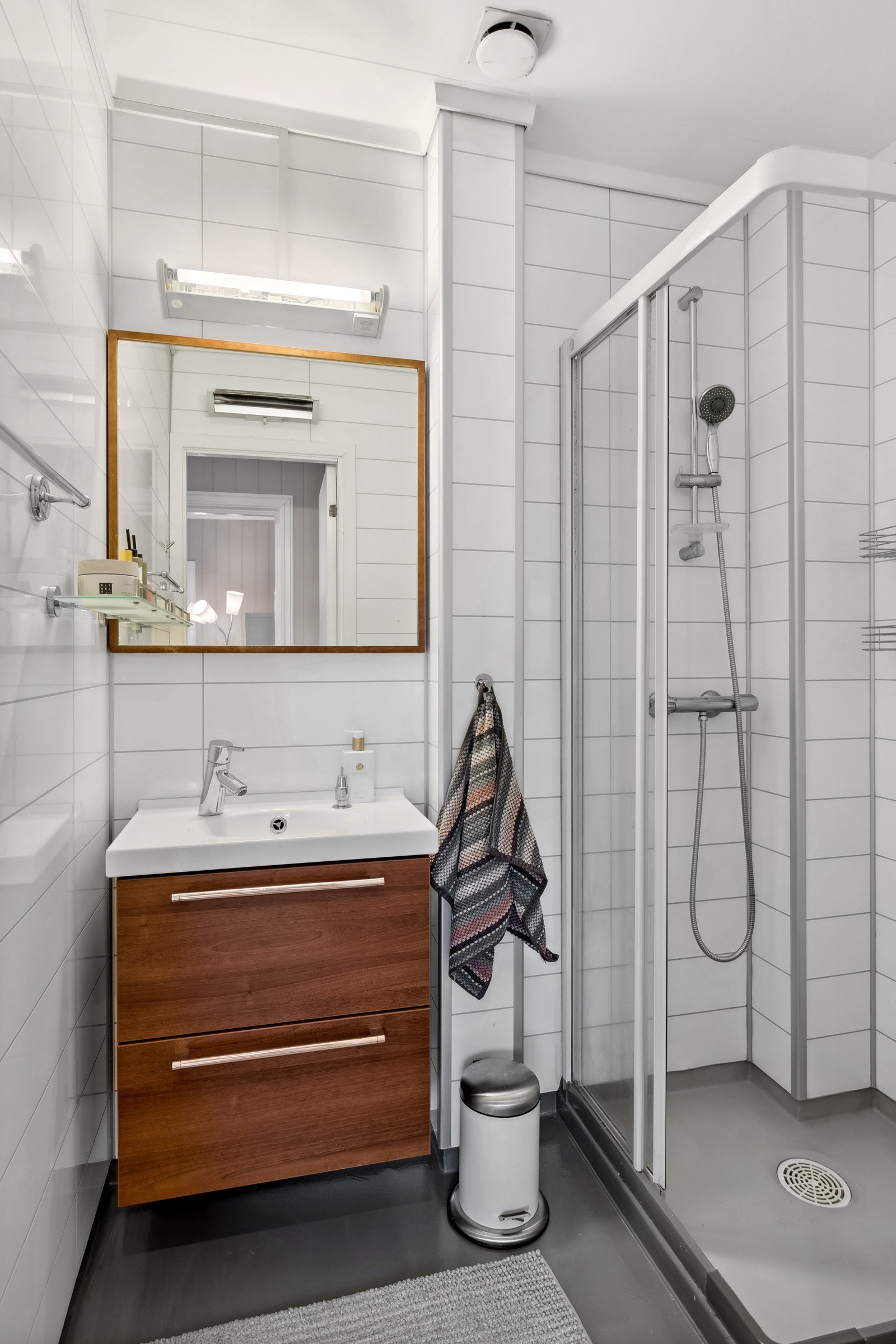 Badet er innredet med grått vinylbelegg pa gulvet og hvite, flismønstrede baderomsplater på veggene. Galleribilde