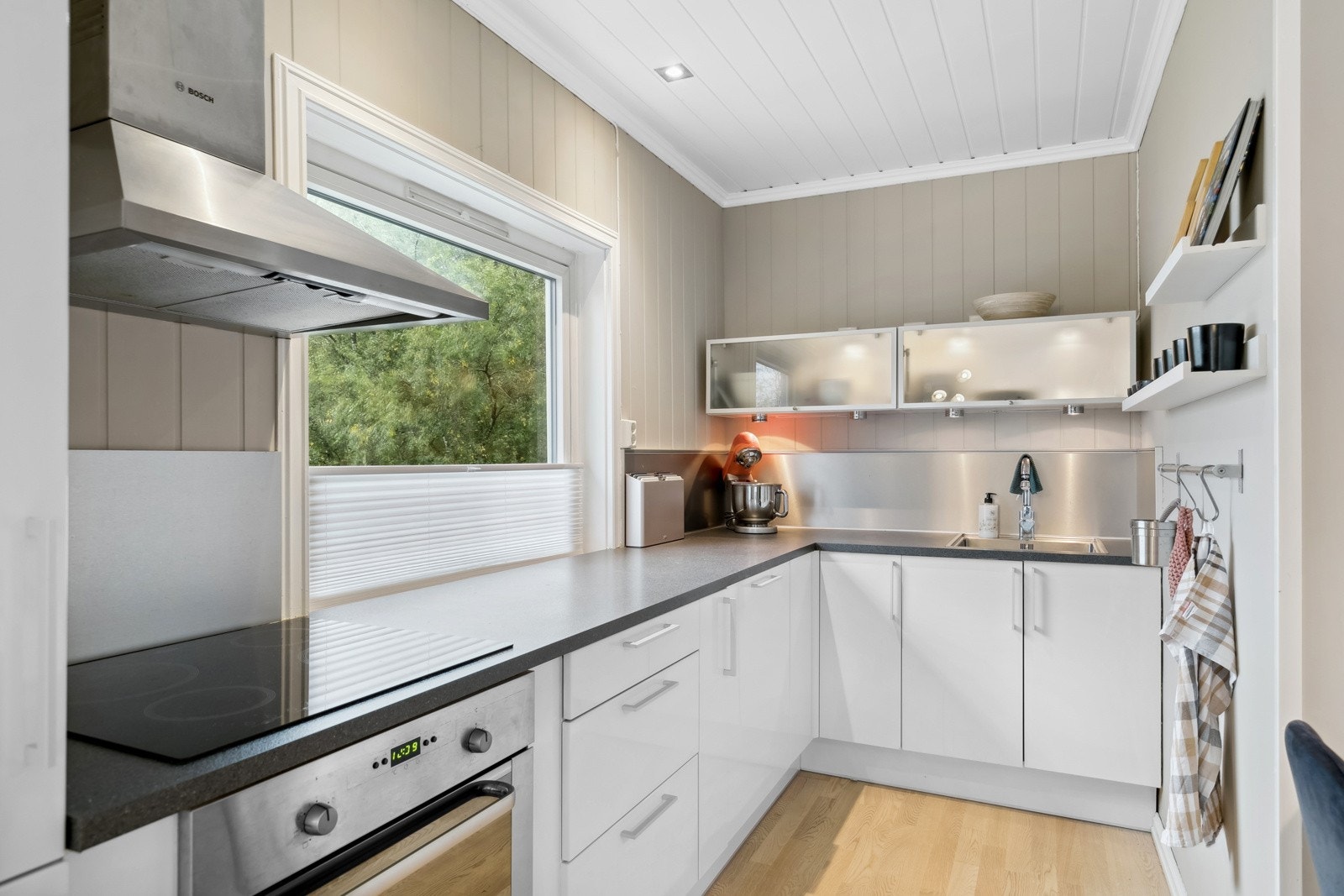 Innredningen fra 2012 har hvite, glatte fronter i høyglans, vitrineskap og grå benkeplate av laminat med nedfelt oppvaskkum. Galleribilde