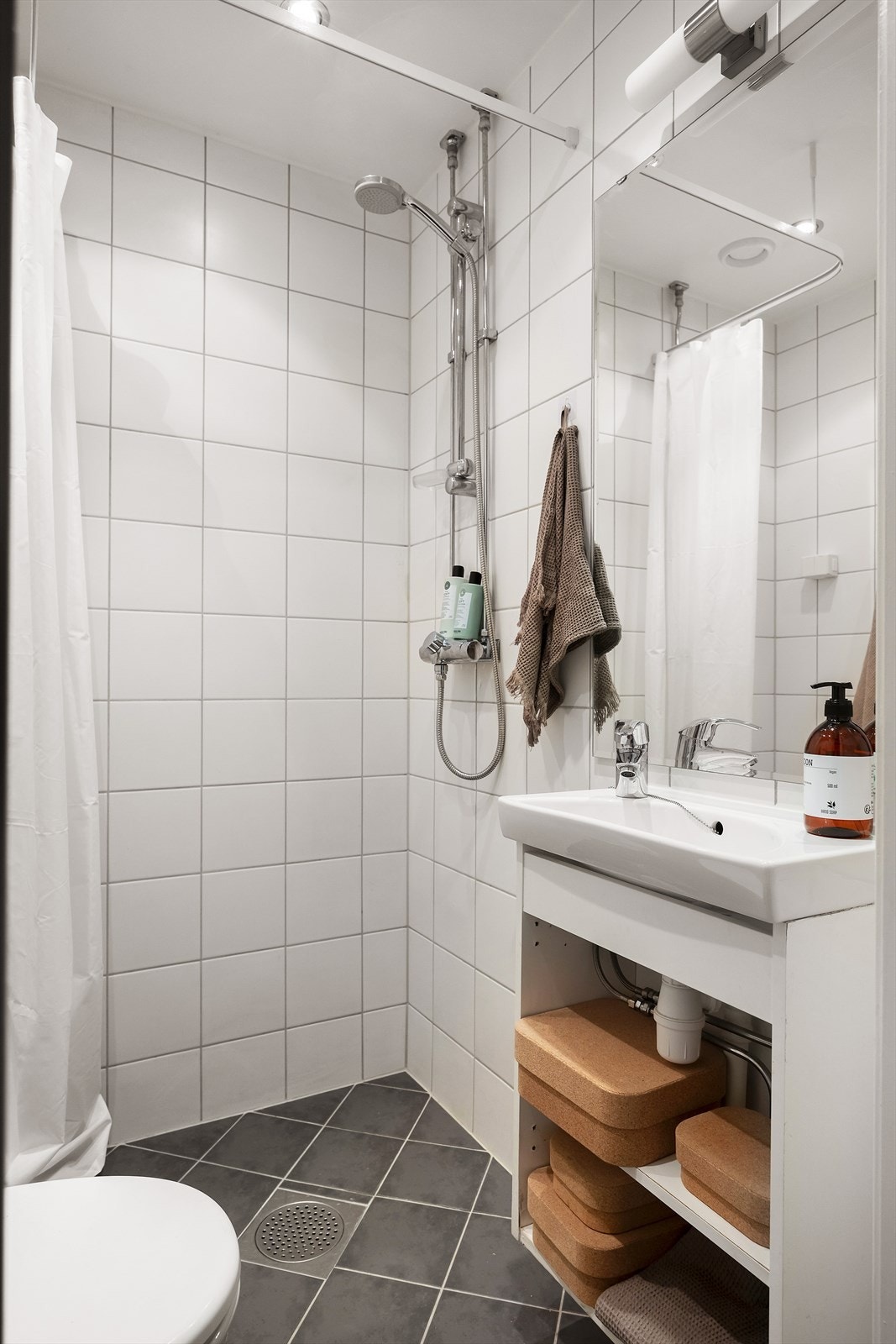 Innredningen består av servant i skapseksjon, veggmontert toalett og dusjhjørne Galleribilde