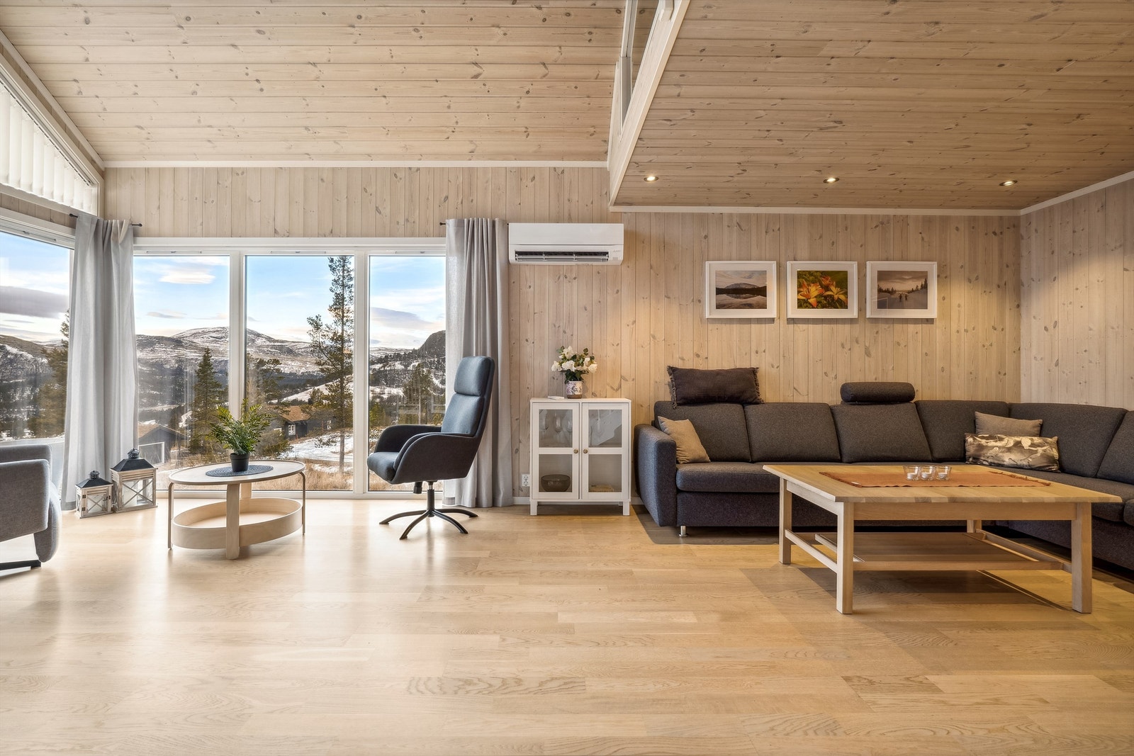 Åpen stue- og kjøkkenløsning med store vindusflater gir god utsikt til den flotte naturen rundt hytta Galleribilde