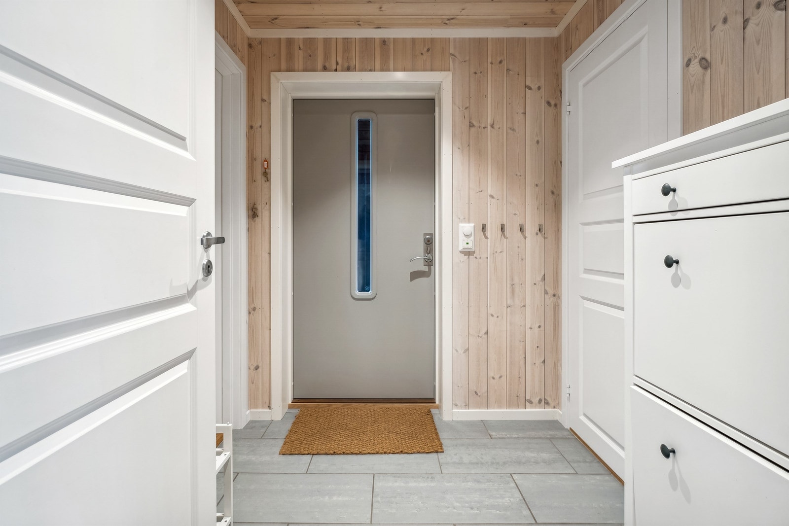 Fra den flislagte entréen med varmekabel i gulvet er det adkomst til bad og vaskerom Galleribilde