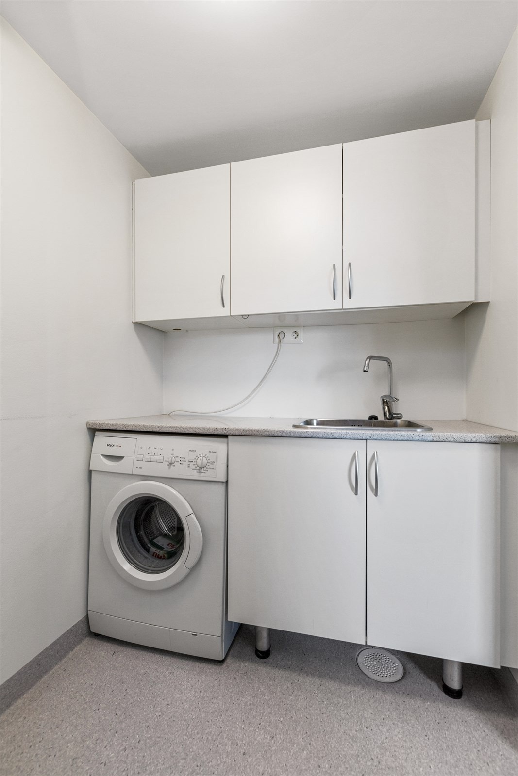 Praktisk vaskerom med opplegg for vaskemaskin og utslagsvask i stål Galleribilde