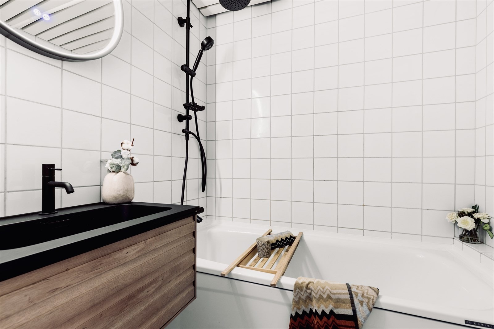 Lyst flislagt baderom med badekar, ny baderomsinnredning og armatur fra 2024. Galleribilde