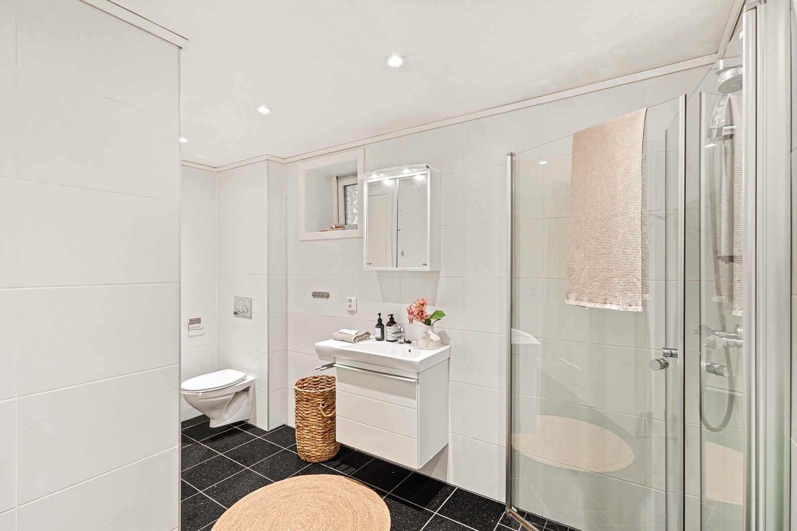 Badet er helfliset og inneholder servant med møblement/speil, vegghengt toalett, dusjgarnityr og innfellbart dusjhjørne Galleribilde