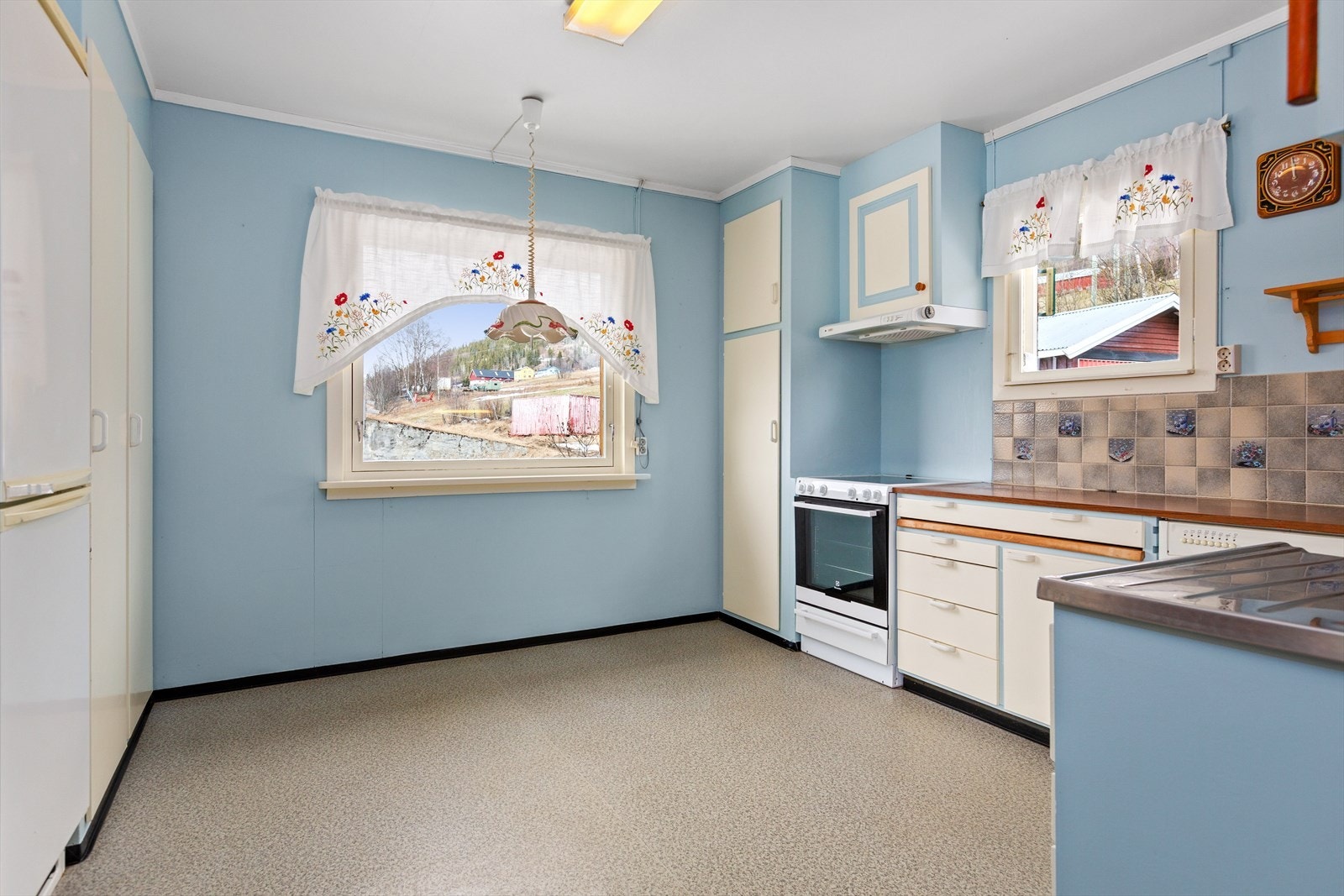 På kjøkkenet er det eldre innredning i malte plater med over- og underskap, samt laminat benkeplate i trefylling med nedfelt oppvaskkum. Nær vinduet er det plass til en mindre spisegruppe. Galleribilde