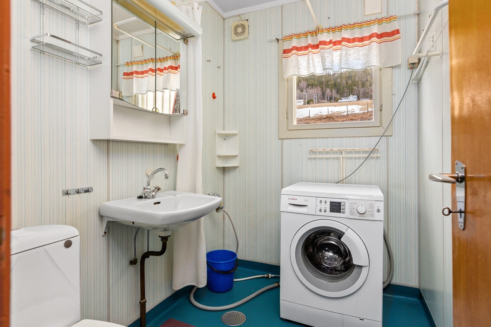 I boligen er det også et eldre bad hvor det må påregnes renovering. På badet er det belegg på gulv og baderomsplater på vegg. Servant og toalett, samt blandebatteri og forheng. Det er opplegg for vaskemaskin, og rommet varmes opp av stråleovn. Galleribilde