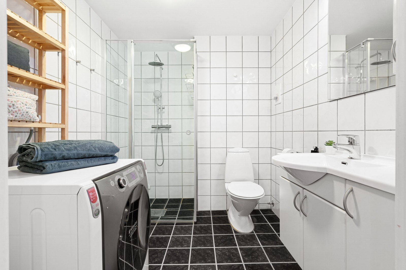 Lekkert flislagt bad med blant annet en oppgradert dusjnisje, varmekabler i gulvet og opplegg for vaskemaskin. Galleribilde