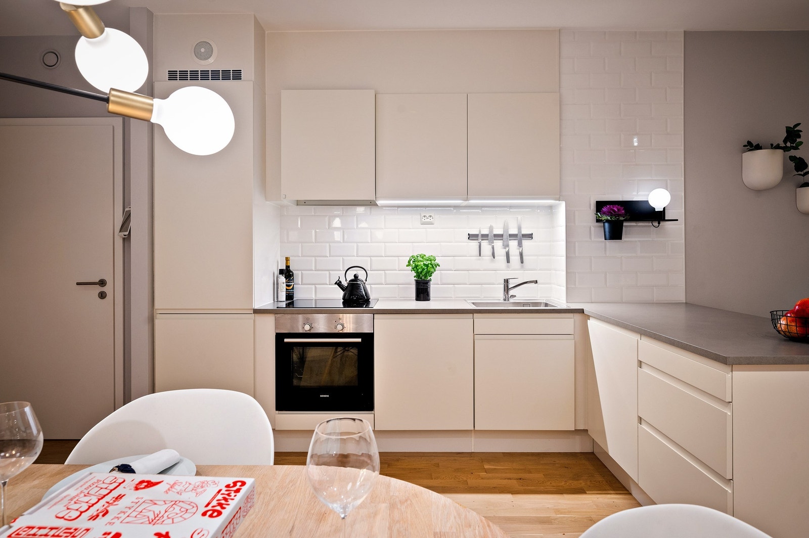 Tidløst og moderne kjøkken fra HTH i åpen løsning med stuen. Kjøkkeninnredningen har lyse, slette fronter og benkeplater av laminat med nedfelt oppvaskkum. Galleribilde